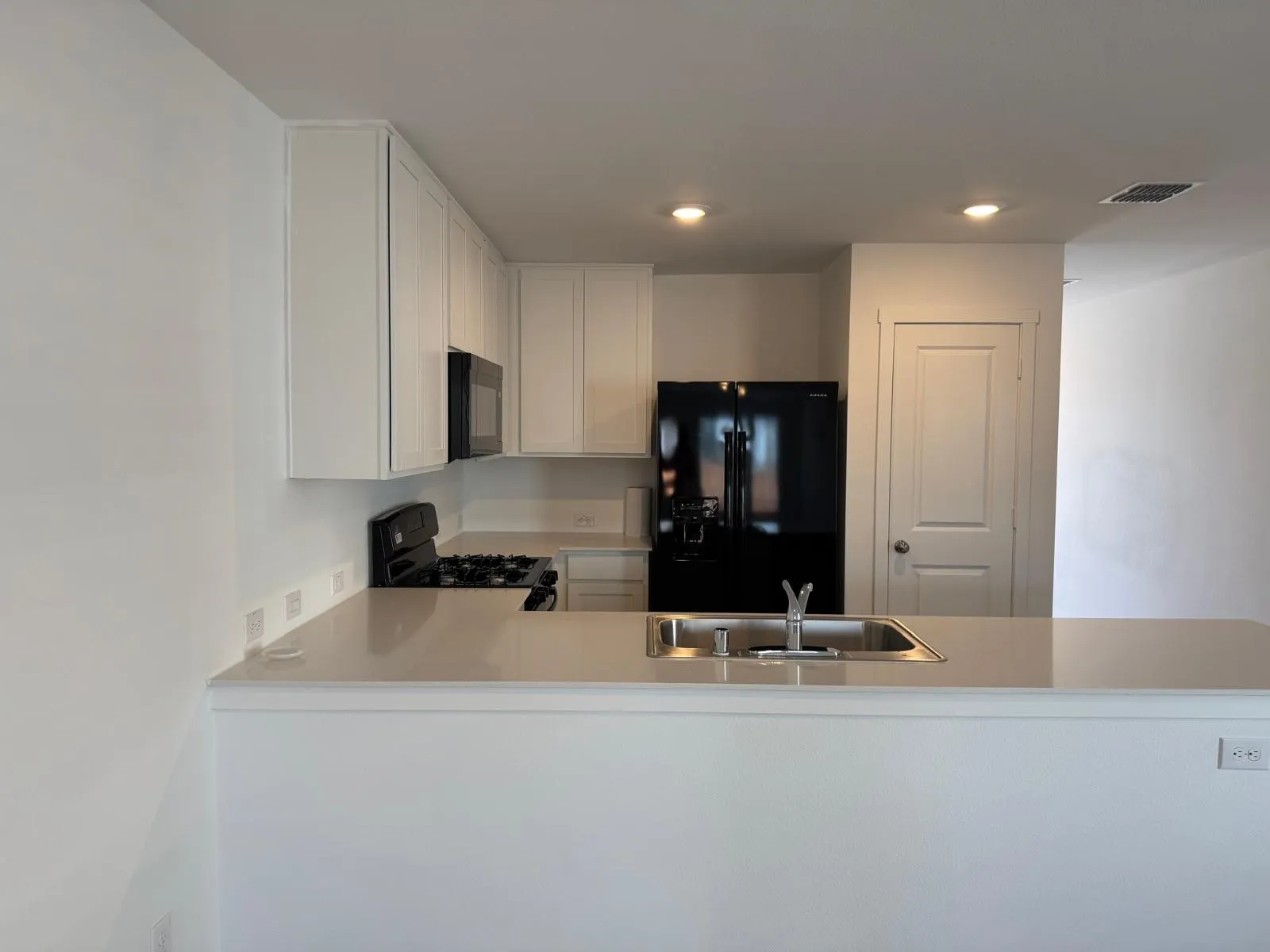 Kitchen featuring black appliances, white cabinetry, light countertops, a peninsula, and recessed lighting