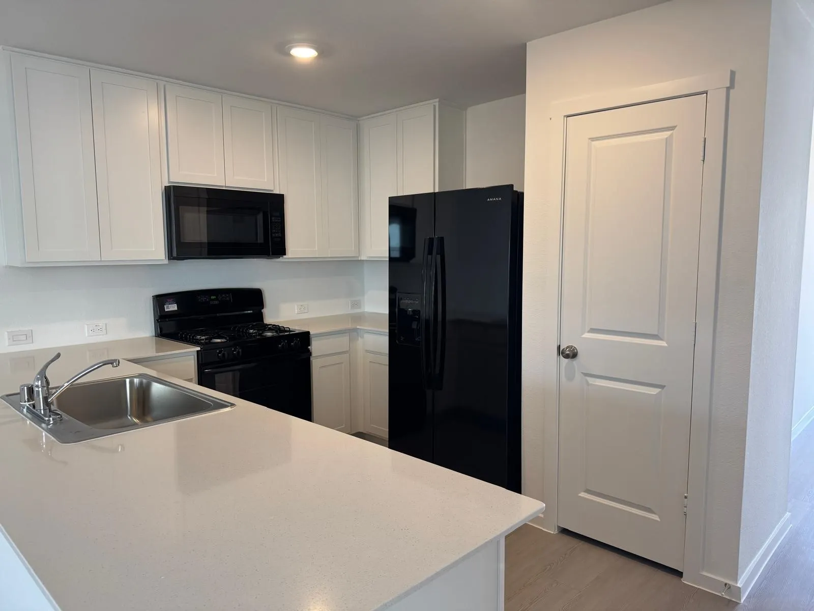 Kitchen with black appliances, light countertops, and white cabinets