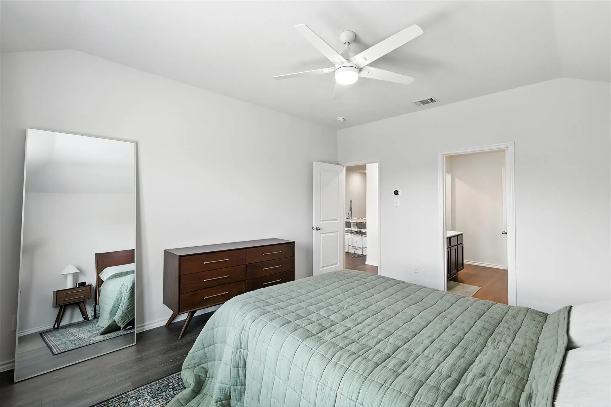 Vaulted ceiling with a ceiling fan, dark wood-finish flooring, and white wall paint