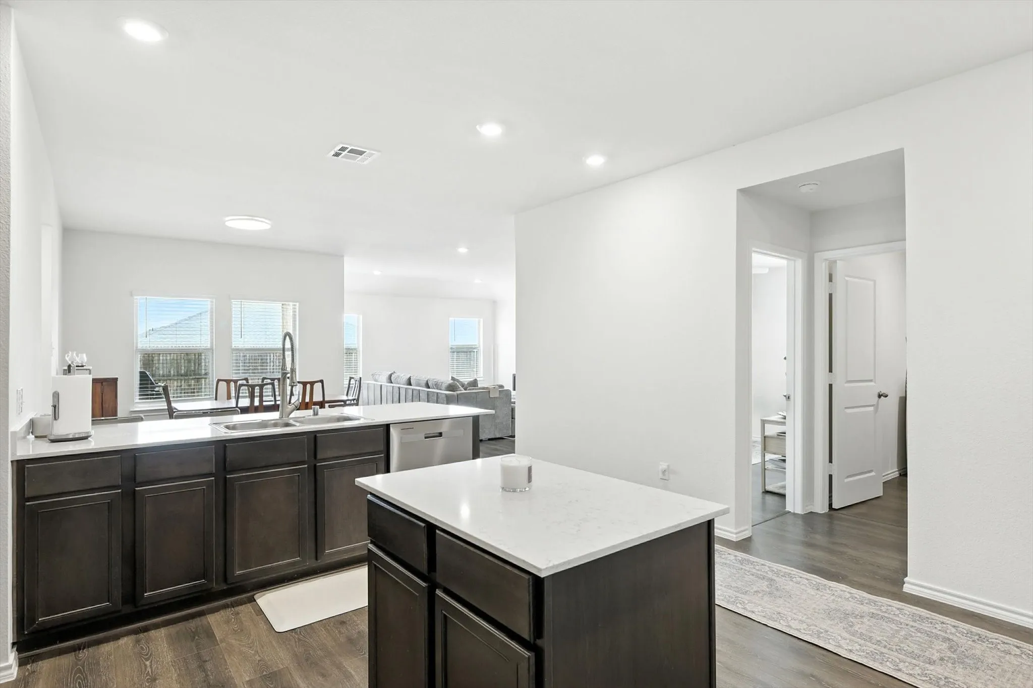 Kitchen featuring dark wood-finish cabinetry, light countertops, an undermount sink with a gooseneck faucet, and stainless steel appliances