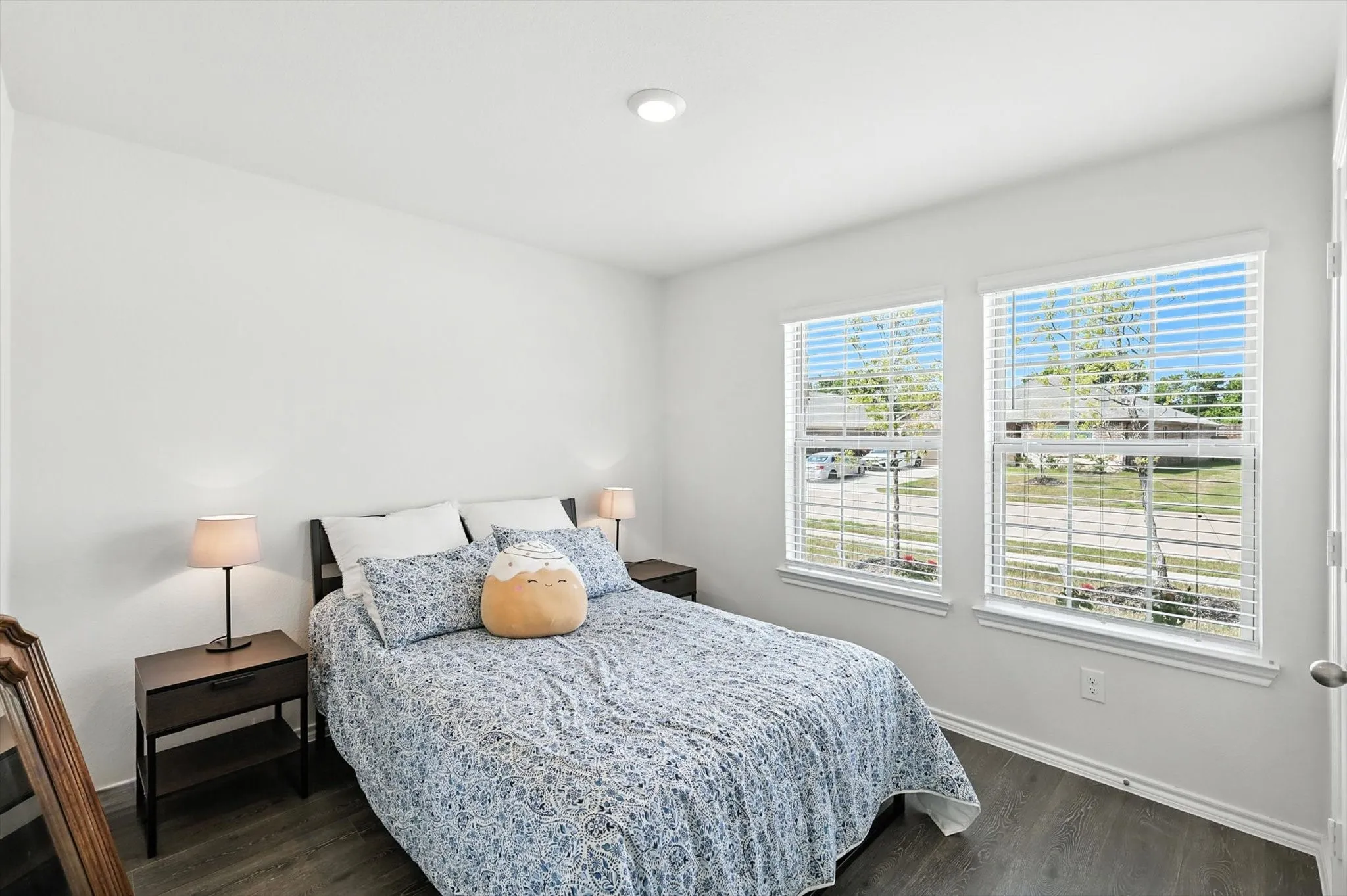 Bright room featuring two windows with horizontal blinds, neutral wall paint, recessed ceiling lighting, and wood-finish flooring
