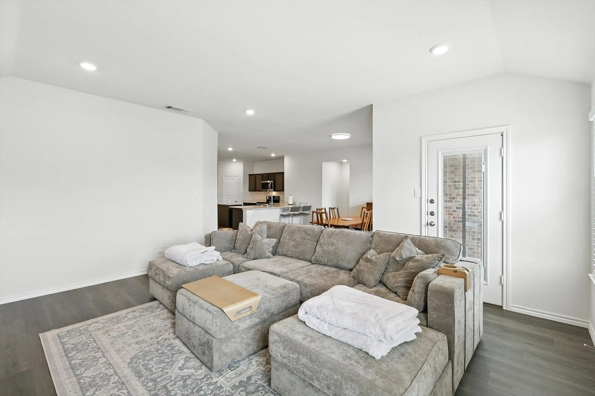 Expansive room with wood-finish flooring, recessed lighting, and a vaulted ceiling