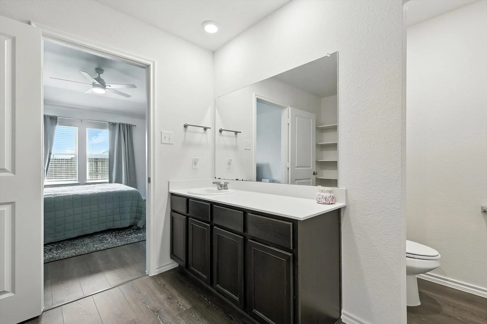 Bathroom vanity with dark wood-finish cabinetry, white countertop, and integrated sink