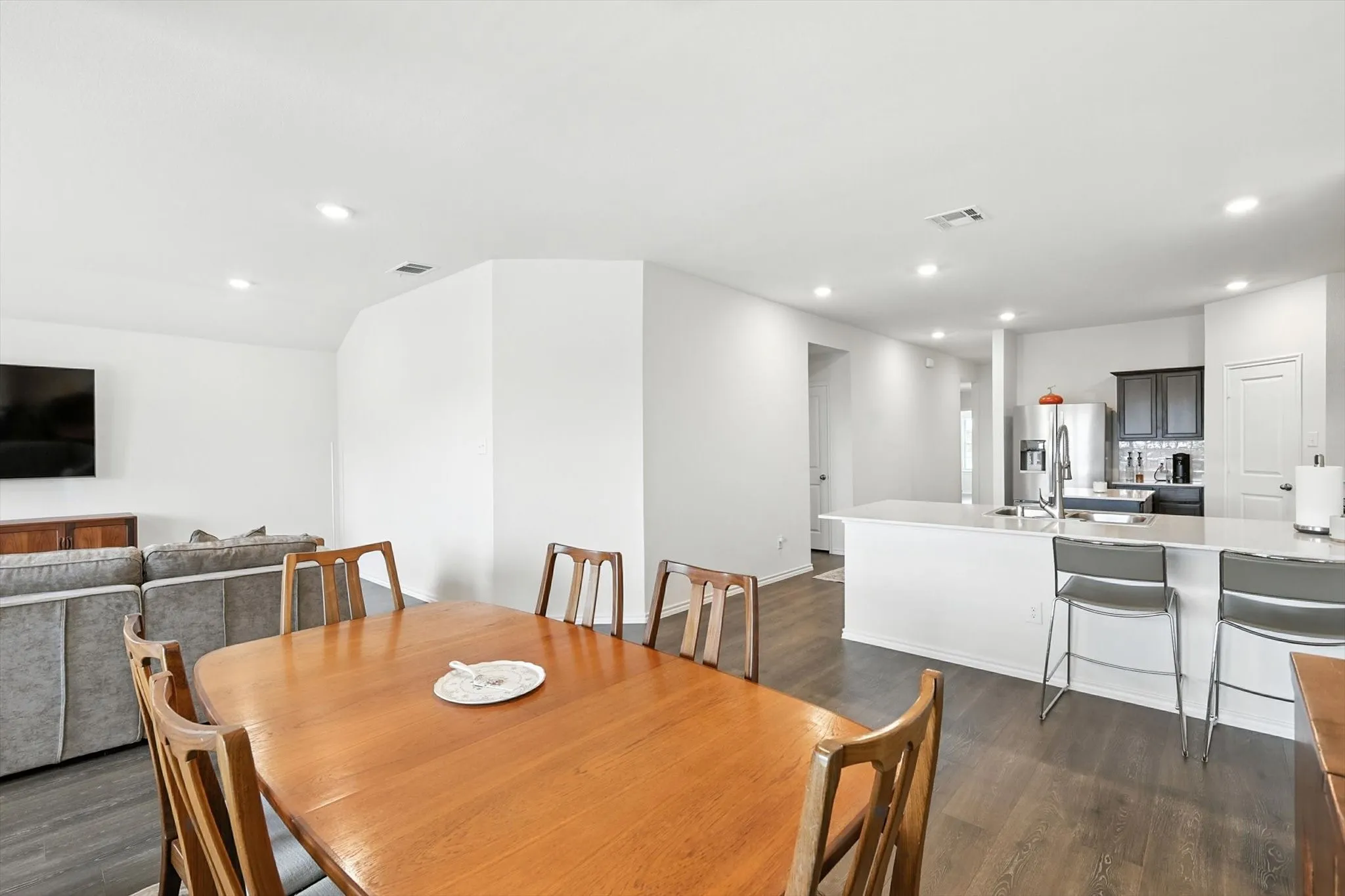 Open-concept layout with wood-finish flooring, recessed lighting, and a kitchen island with seating