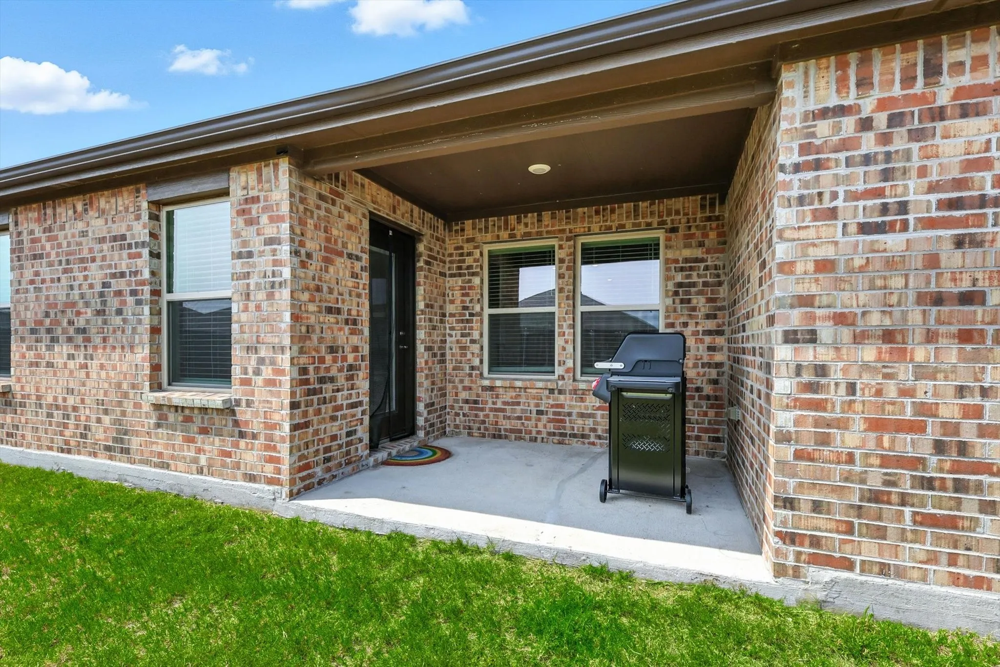 Covered patio with concrete flooring, brick exterior, and recessed ceiling lighting