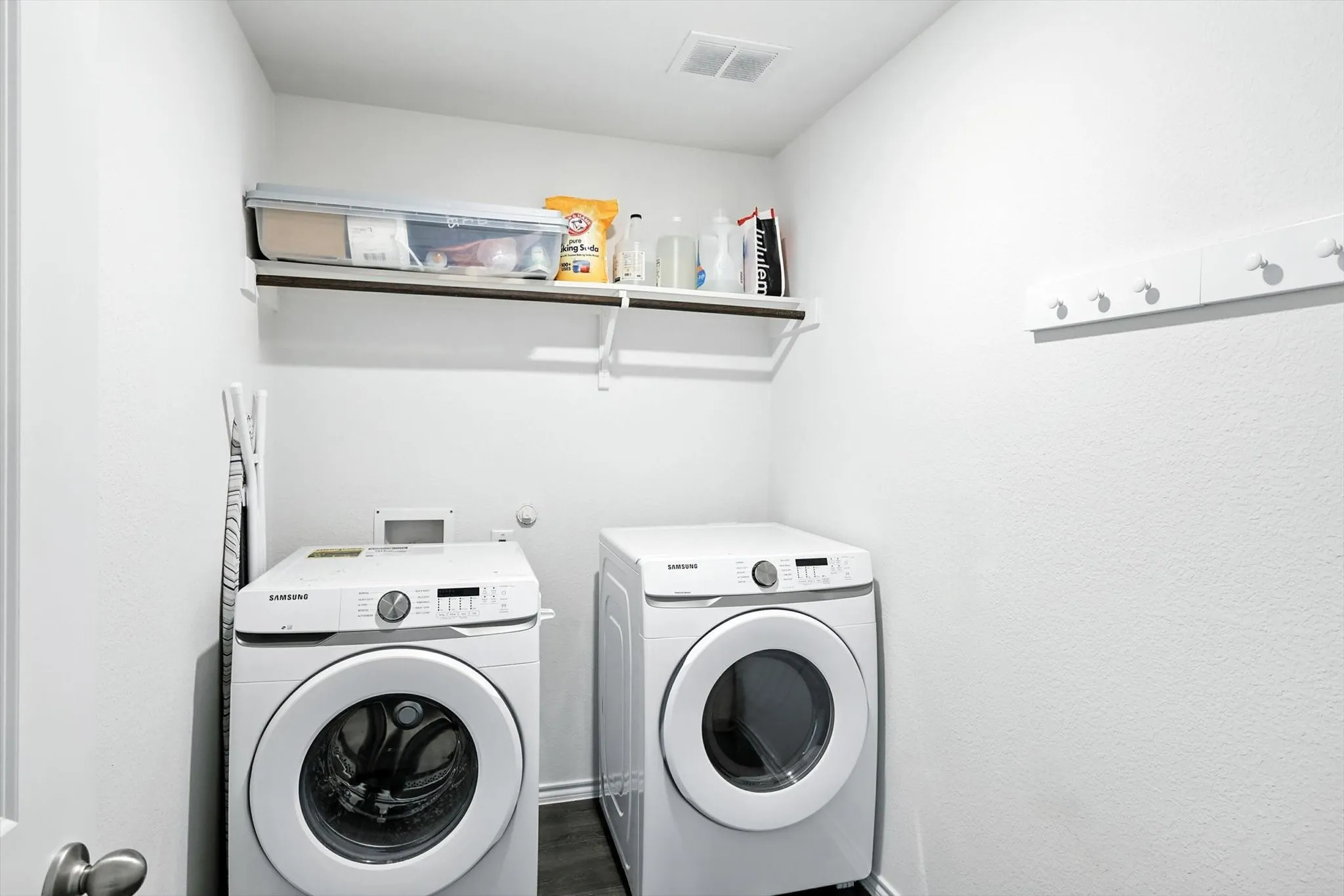 Laundry area with a built-in shelf, wall-mounted coat rack, and dark wood-finish flooring
