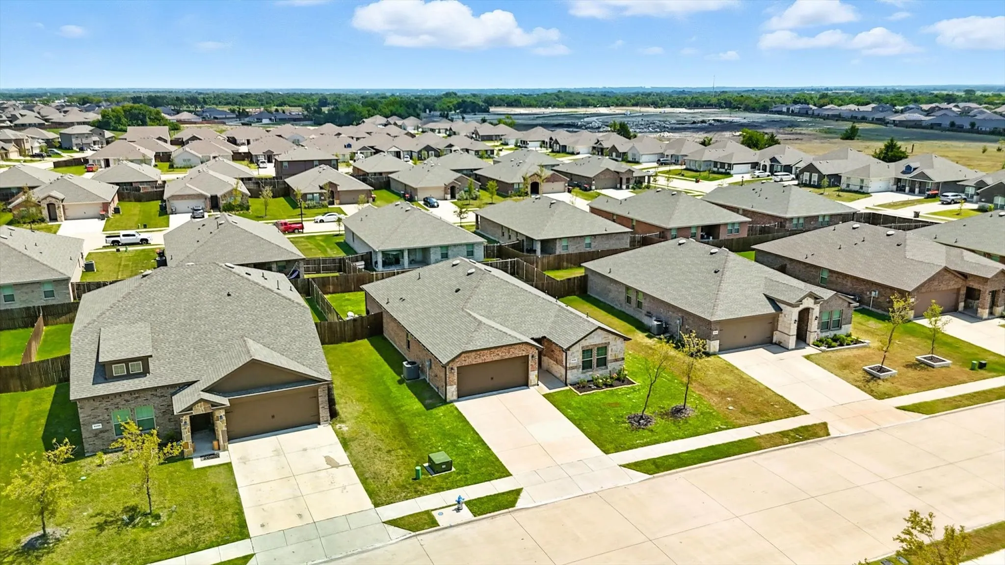 Residential neighborhood featuring brick exteriors, attached garages, paved driveways, and manicured lawns