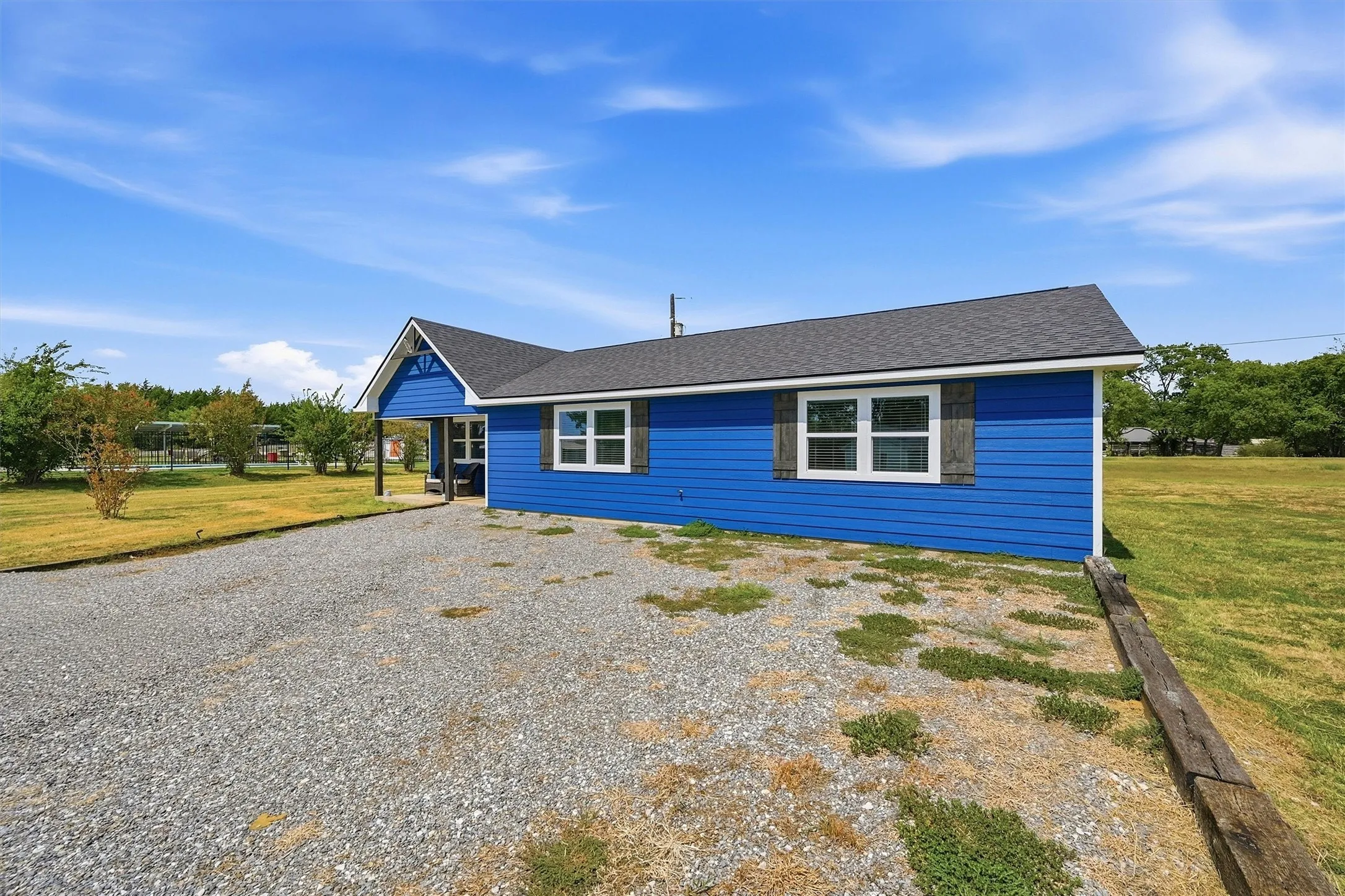 Blue exterior siding with white trim, dark gray architectural shingle roof, white-framed windows, and a covered entry