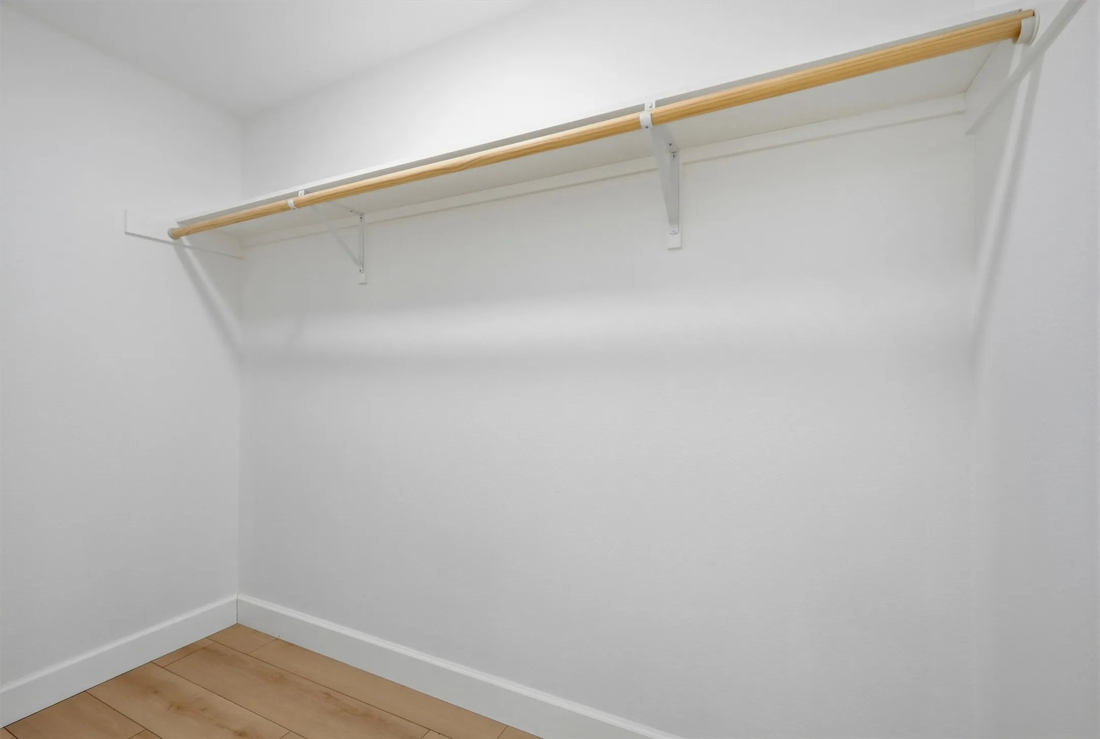 Built-in shelving with hanging rod and wood-finish flooring