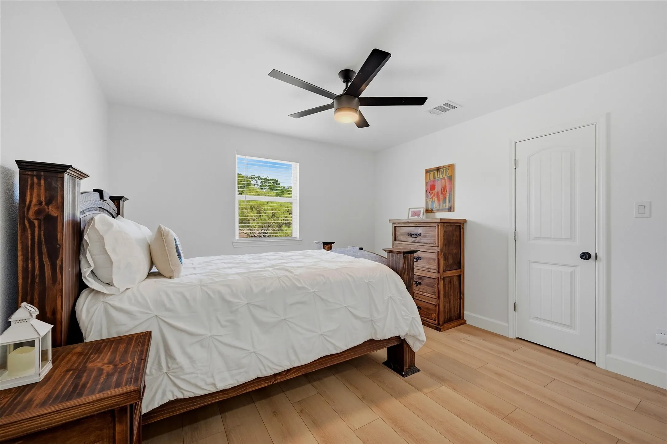 Vaulted ceiling with a black ceiling fan, white walls, wood-finish flooring, and a window with blinds