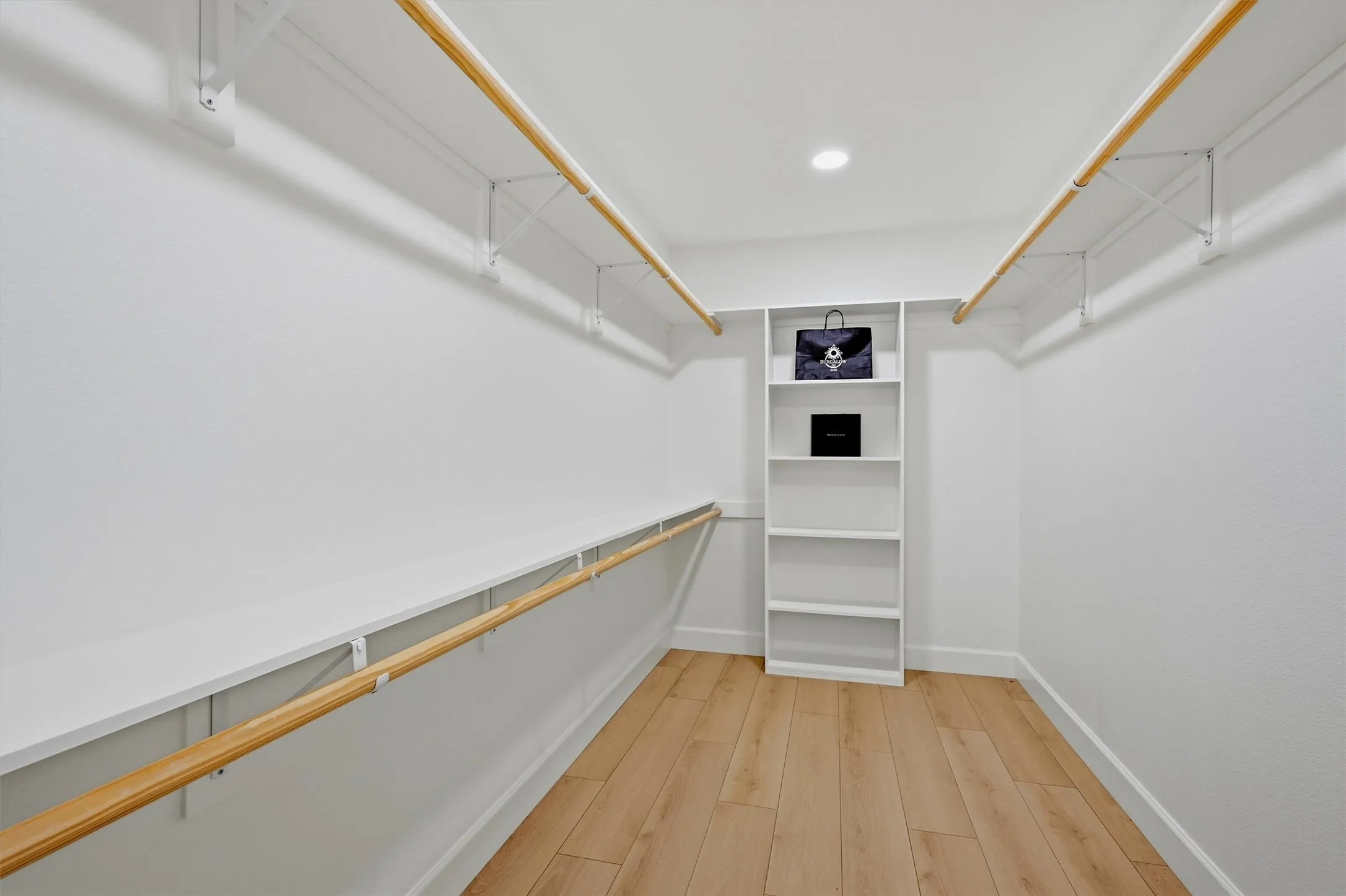 Walk-in closet featuring wood-finish flooring, recessed lighting, built-in shelving, and wood rods