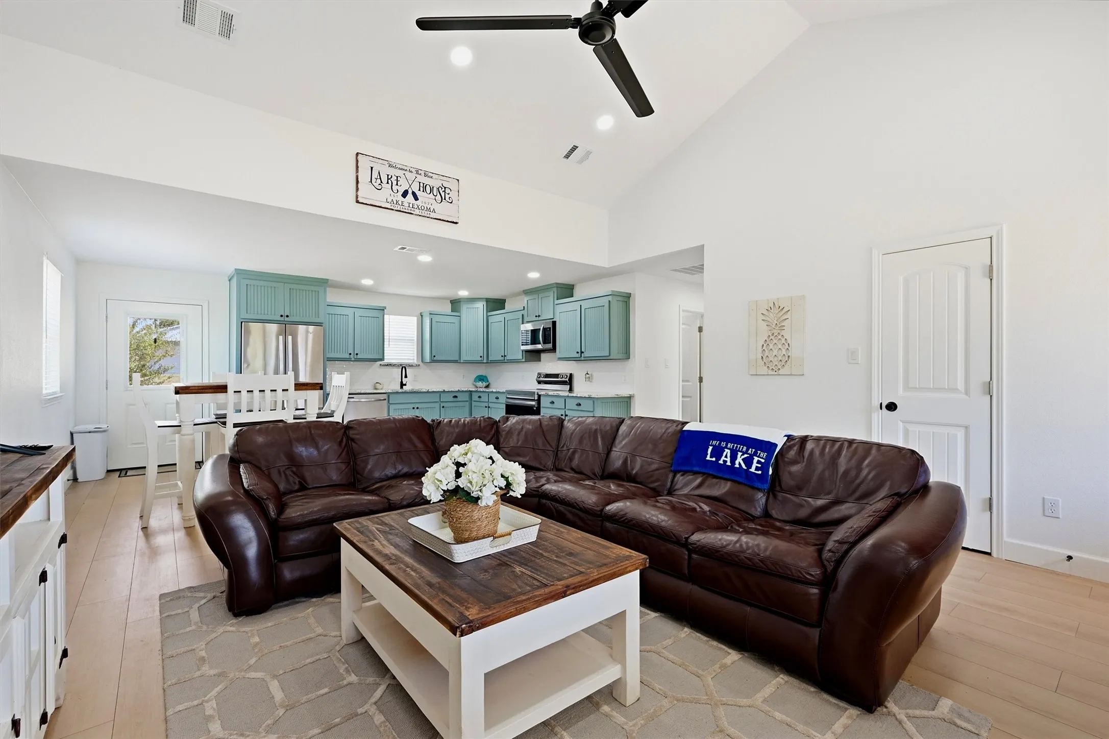 Vaulted ceiling with a ceiling fan, light wood-finish flooring, and white walls