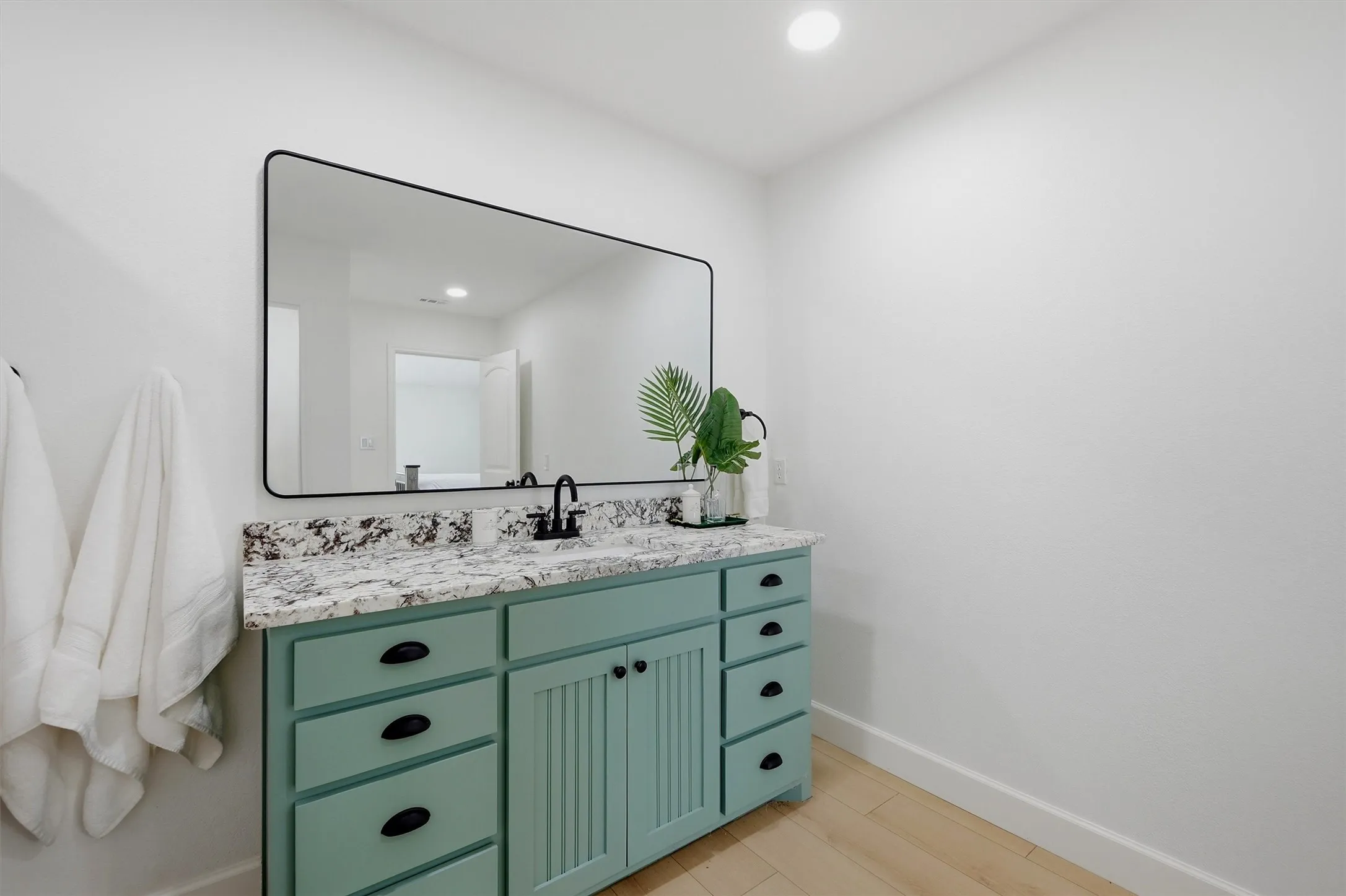 Custom vanity with integrated sink, stone countertop, matte black faucet, and large rectangular mirror