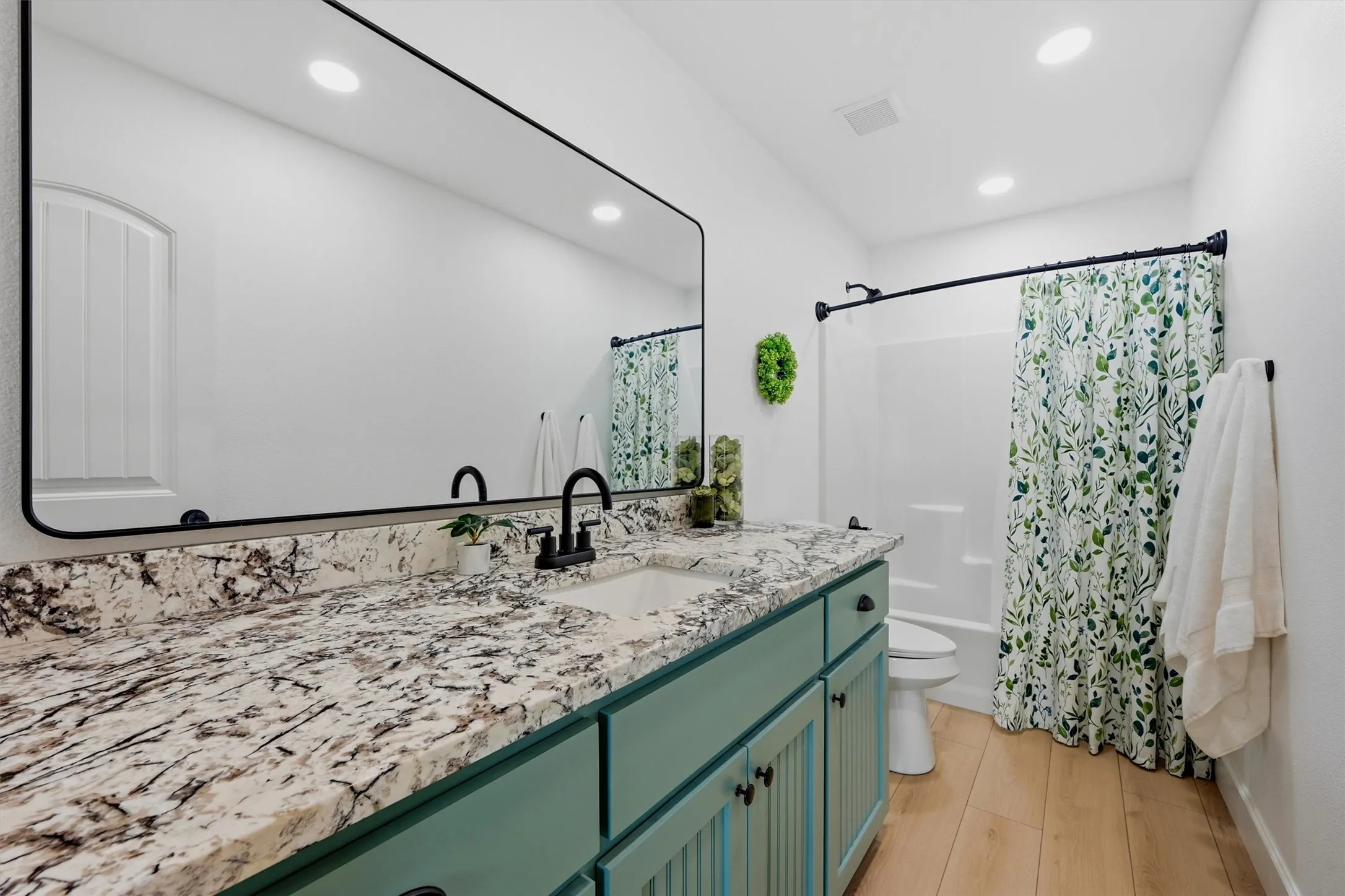 Long vanity with a stone-finish countertop, under-mount sink, and matte black faucet