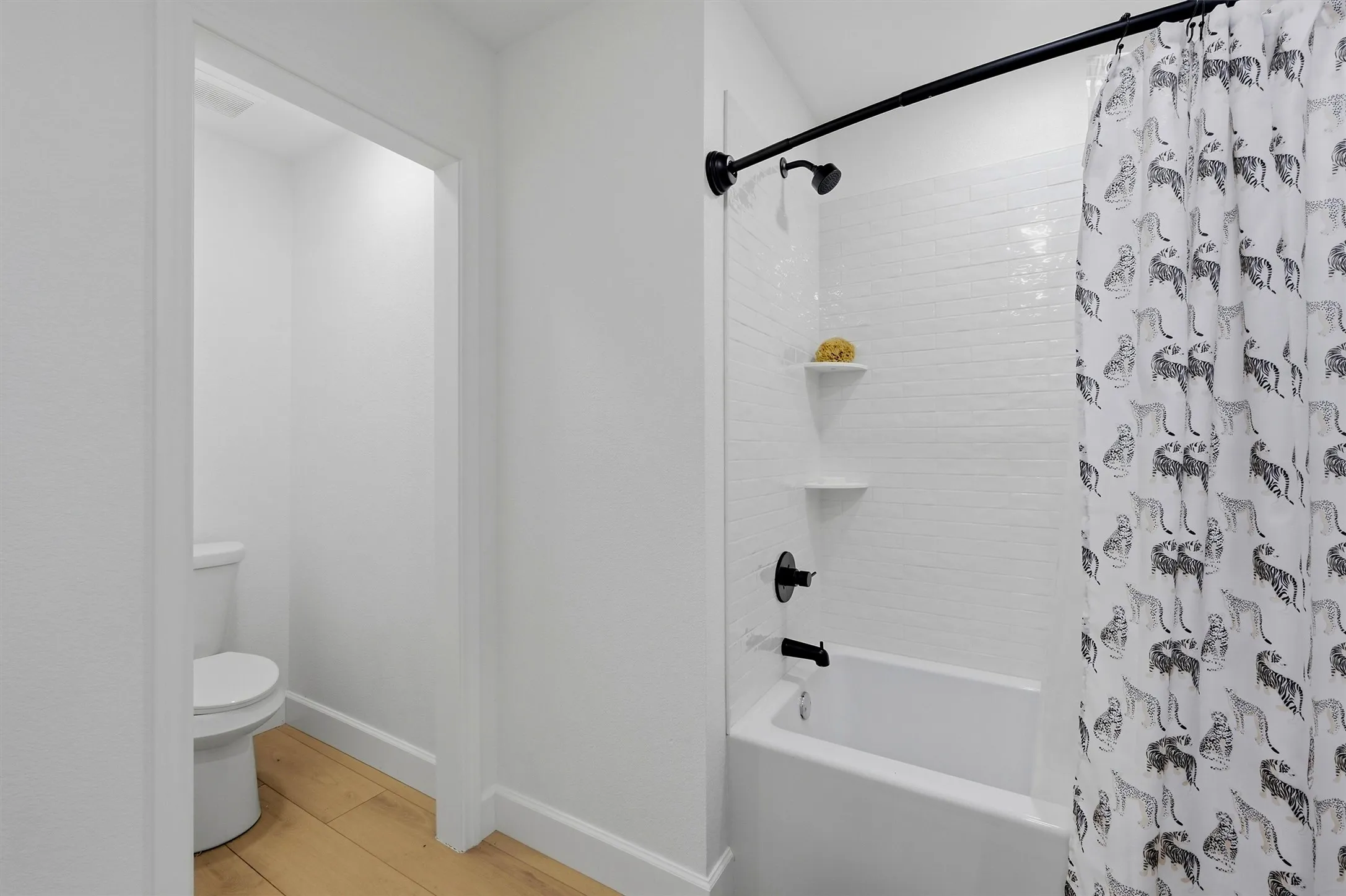 Bathtub with matte black fixtures, white subway tile surround, and built-in shelving
