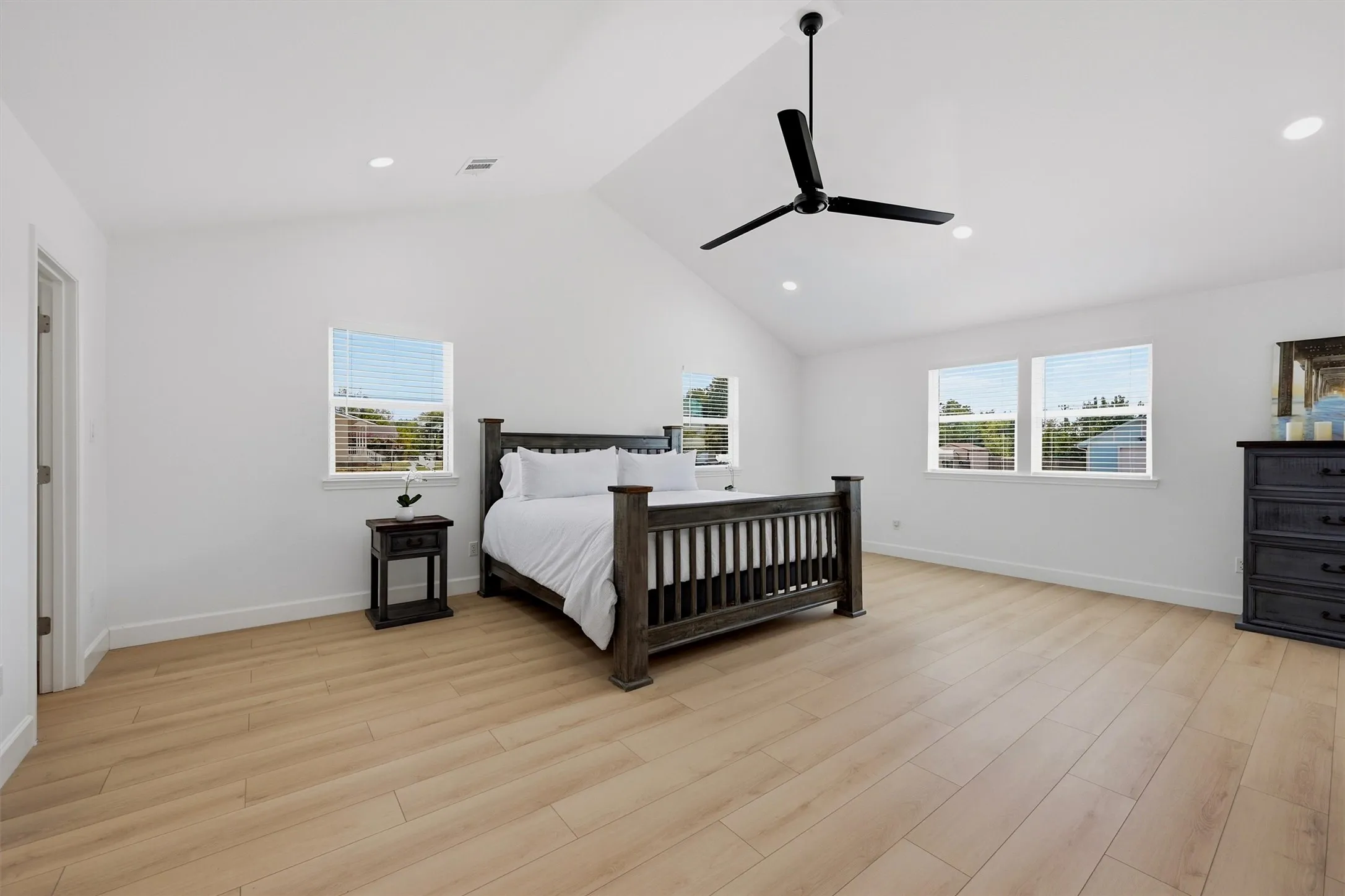 Vaulted ceiling with a contemporary ceiling fan, recessed lighting, wood-finish flooring, and multiple windows