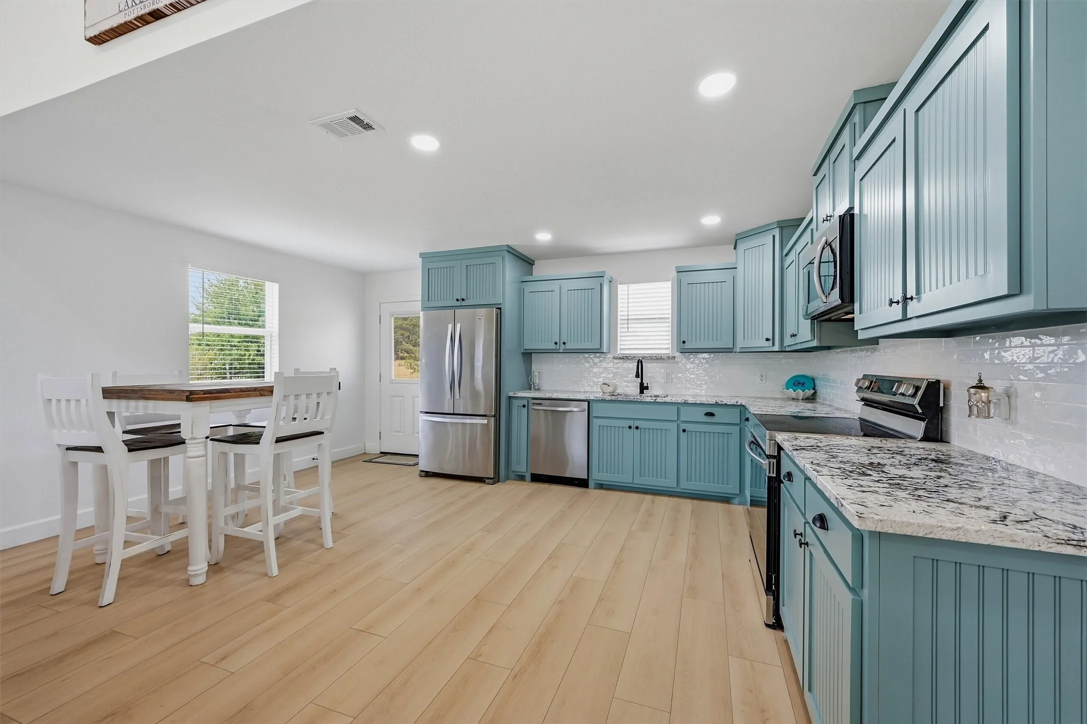 Kitchen featuring light wood-finish flooring, recessed lighting, and a white subway tile backsplash