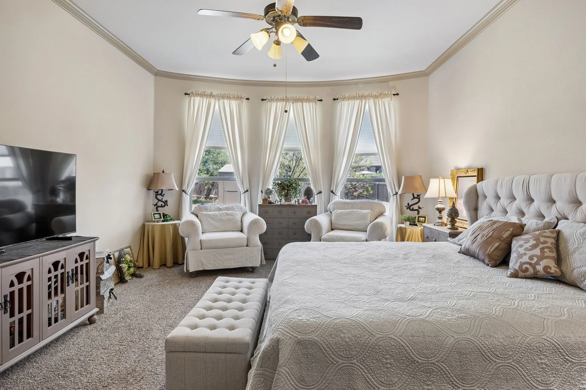 Recessed bay window with three large windows, crown molding detail, and a ceiling fan with integrated lighting