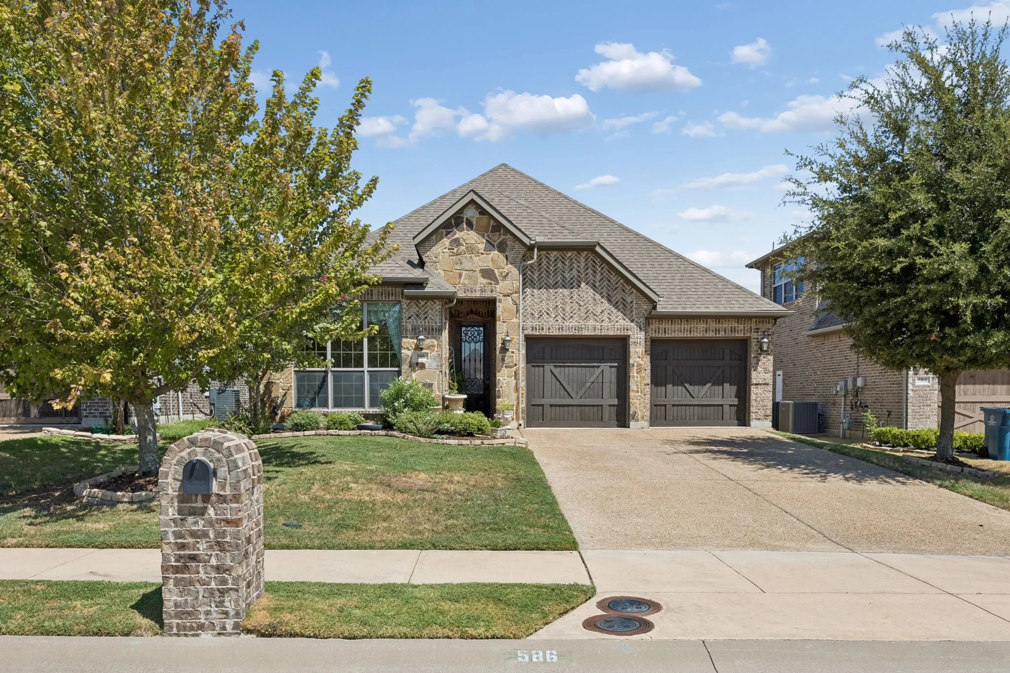 Brick and stone facade with a covered entry, an attached two-car garage, and a concrete driveway