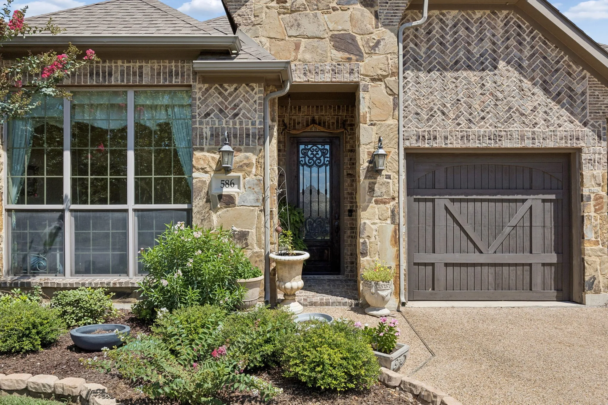 Stone and brick facade with herringbone pattern accents, large front window, and an ornate entry door