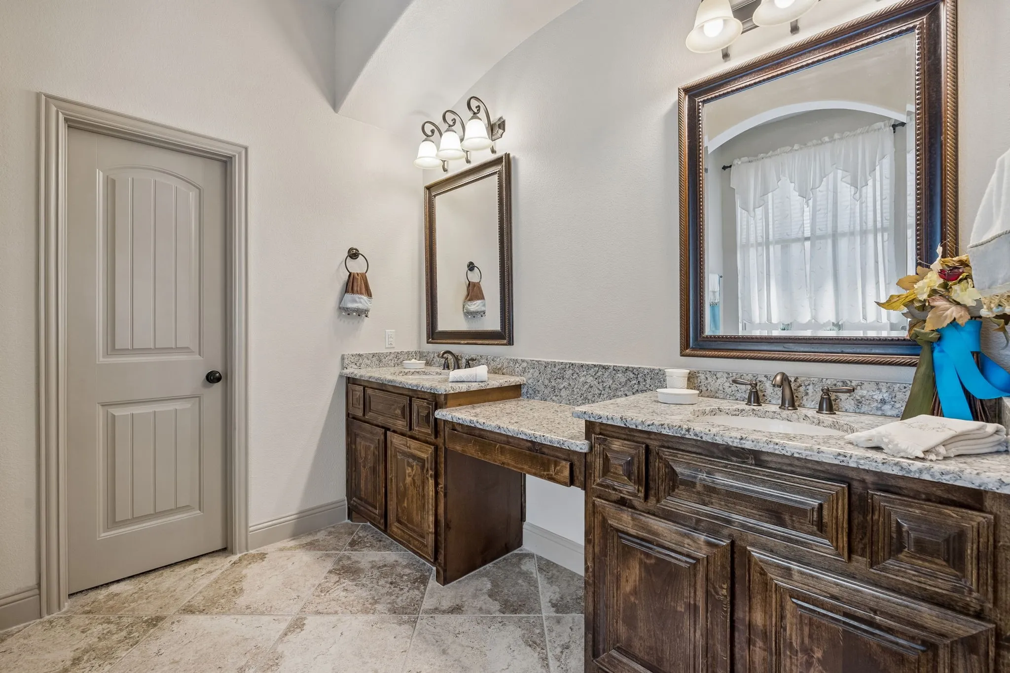 Dual wood-finish vanity with granite countertops, integrated sinks, and bronze-finish fixtures
