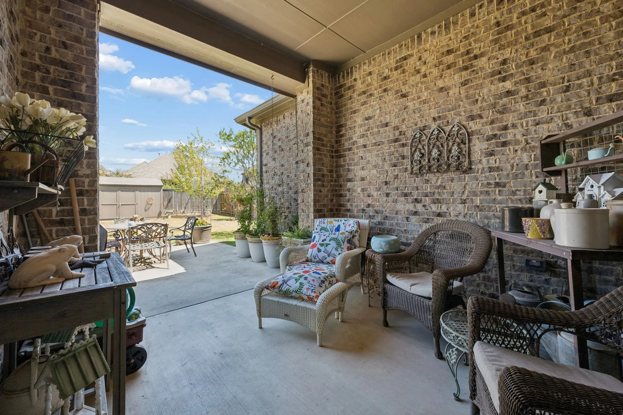 Covered patio with brick walls, concrete flooring, and an open-air extension