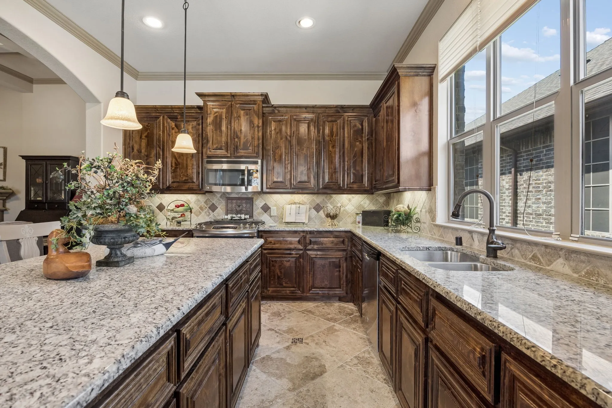 Kitchen featuring granite countertops, dark wood-finish cabinetry, stainless steel appliances, and a tile backsplash