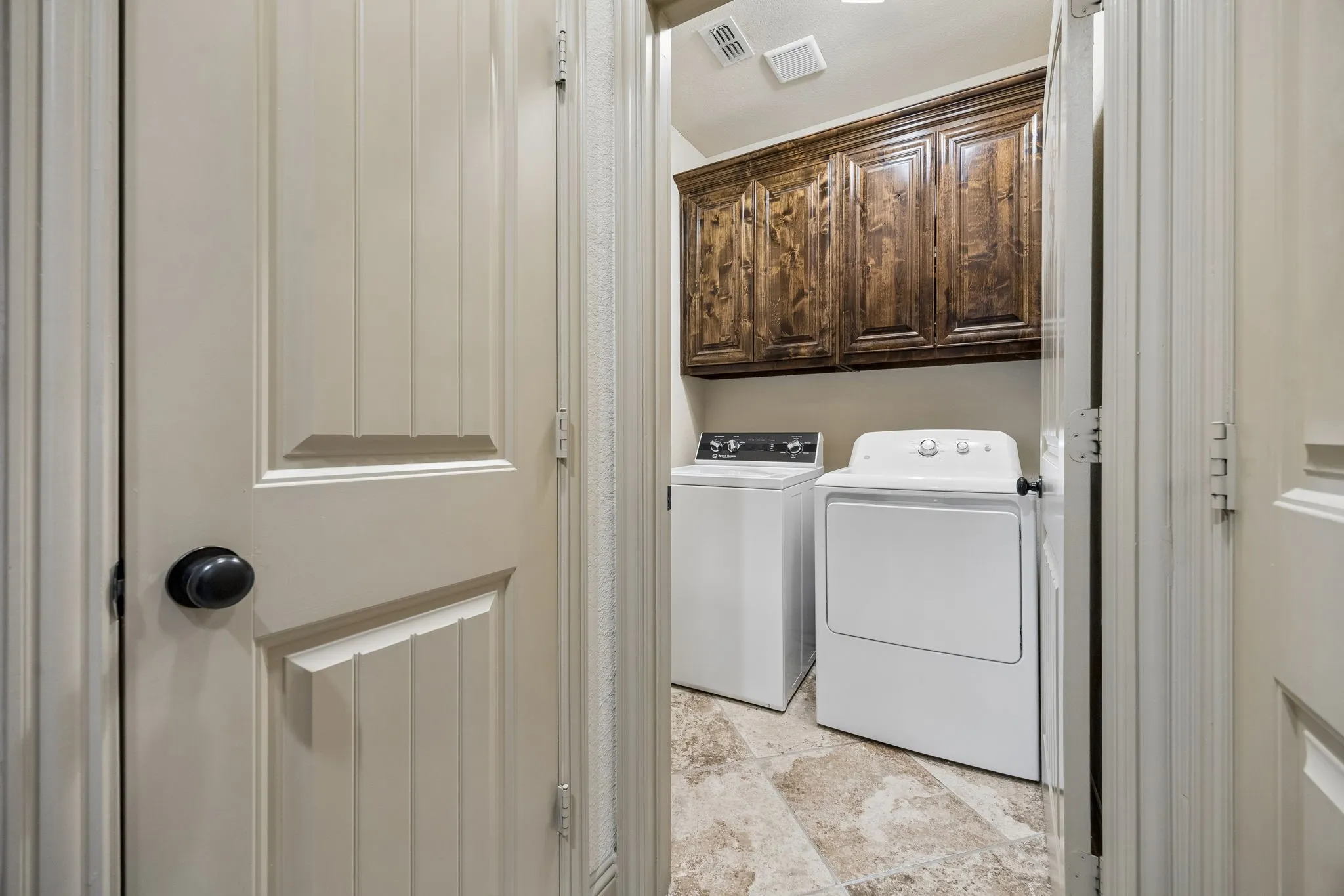 Laundry area featuring wood-finish cabinetry and tile flooring