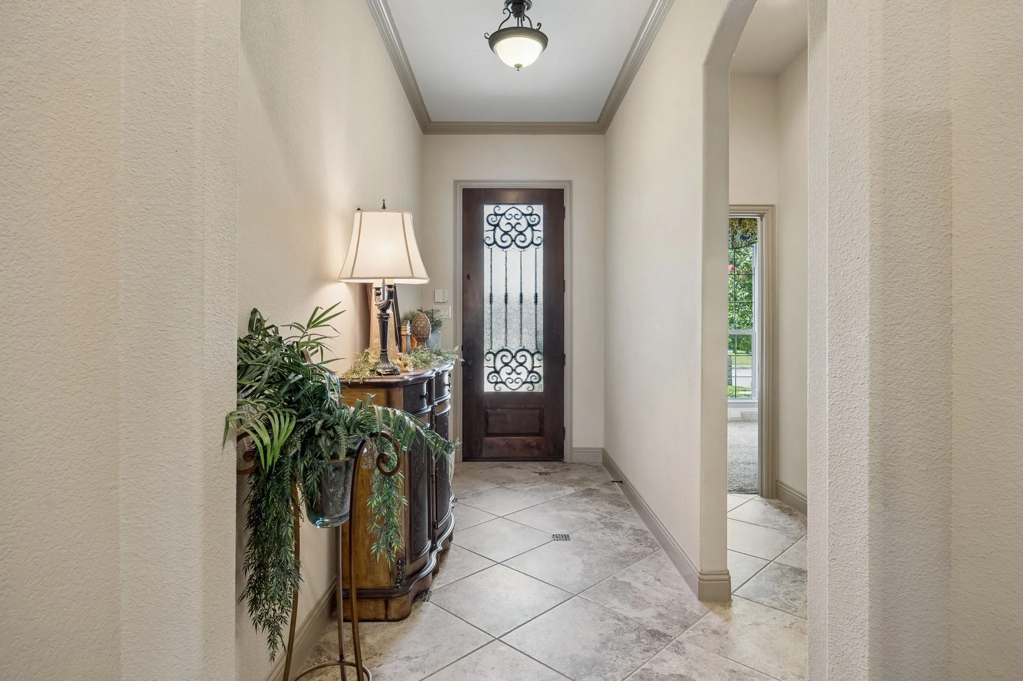 Entryway with tiled flooring, decorative wood entry door, arched doorway, and crown molding