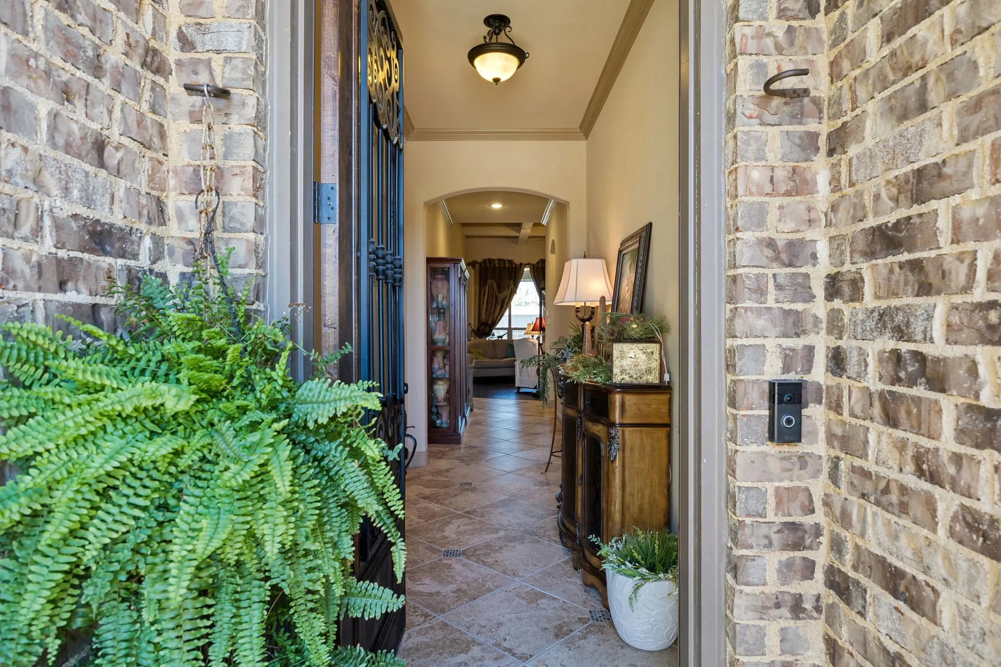 Brick exterior entry featuring a decorative wrought iron door and a recessed ceiling light