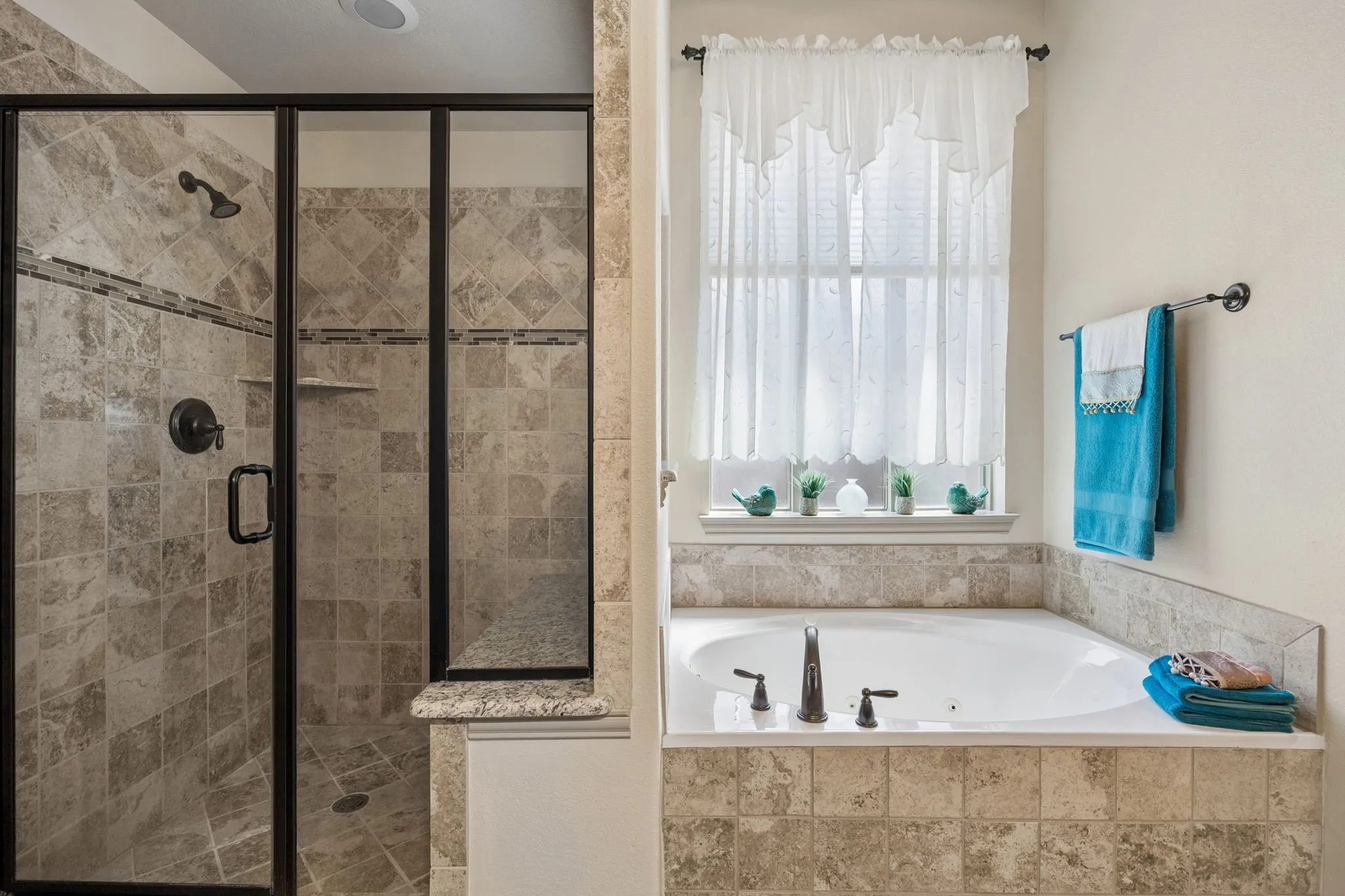Enclosed shower with decorative tile and built-in bench, jetted soaking tub, and tile surround