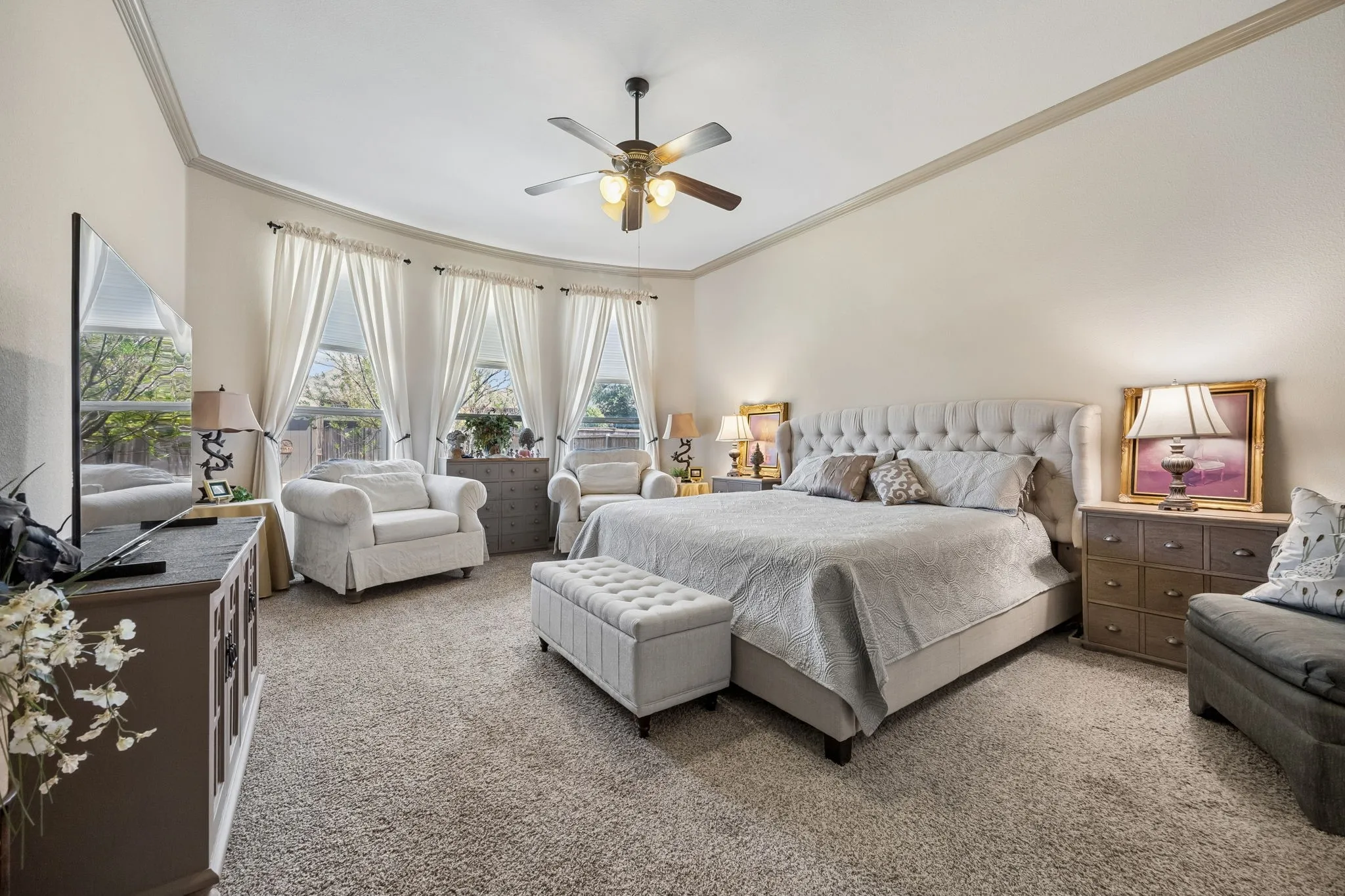 Spacious room featuring carpeting, a ceiling fan with light fixture, and multiple windows