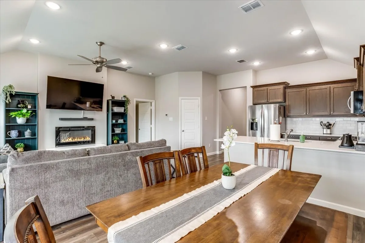 Vaulted ceilings with recessed lighting, wood-finish flooring, a contemporary fireplace, and a kitchen featuring stainless steel appliances and wood cabinetry