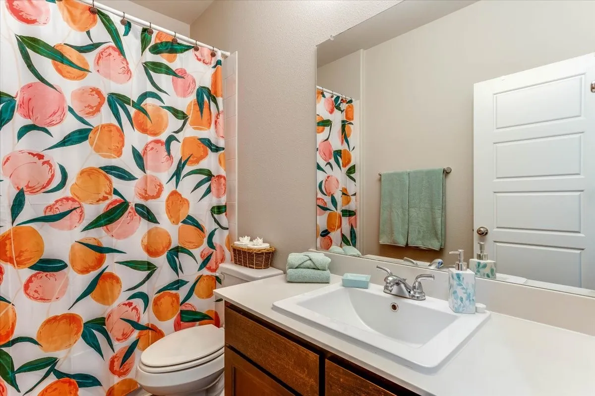 Bathroom featuring a drop-in sink with chrome fixtures, wood-finish vanity cabinetry, and a large wall-mounted mirror