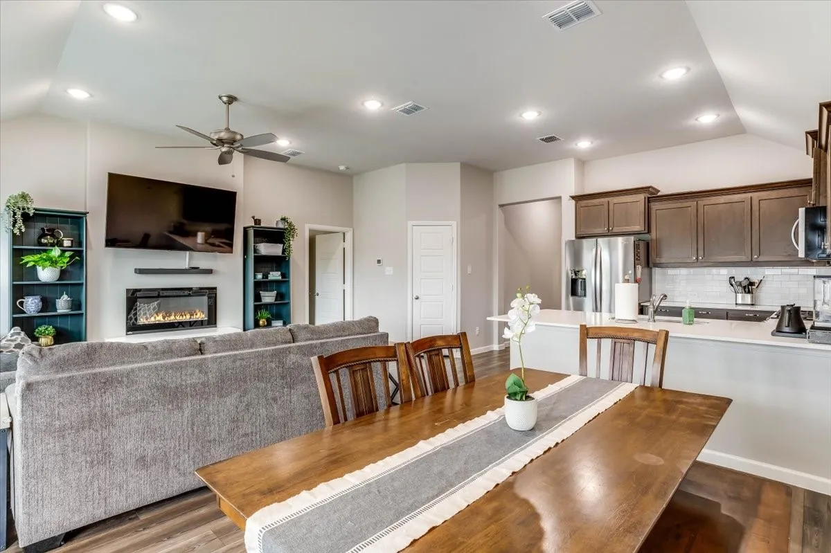 Open-concept living space featuring a built-in fireplace, wood-finish flooring, recessed lighting, and a ceiling fan