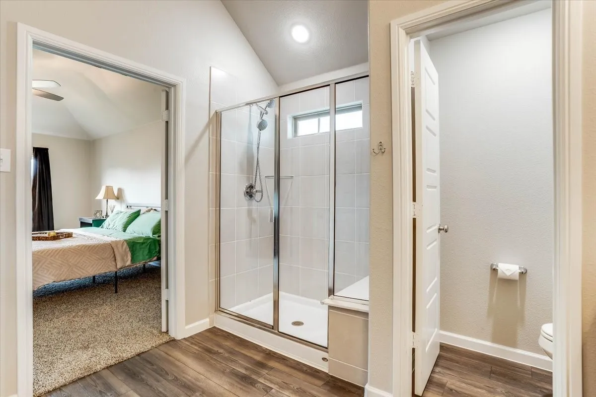 Glass-enclosed shower with a built-in bench, tiled walls, and brushed nickel fixtures