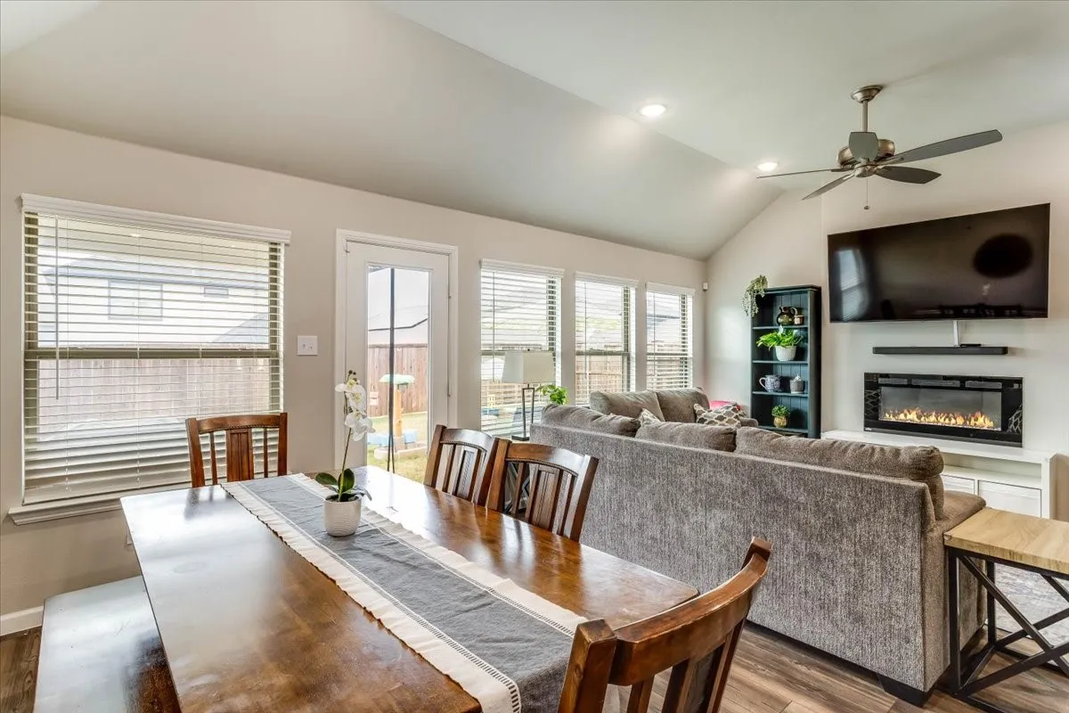 Vaulted ceiling with recessed lighting, wood-finish flooring, multiple windows with blinds, and a built-in electric fireplace