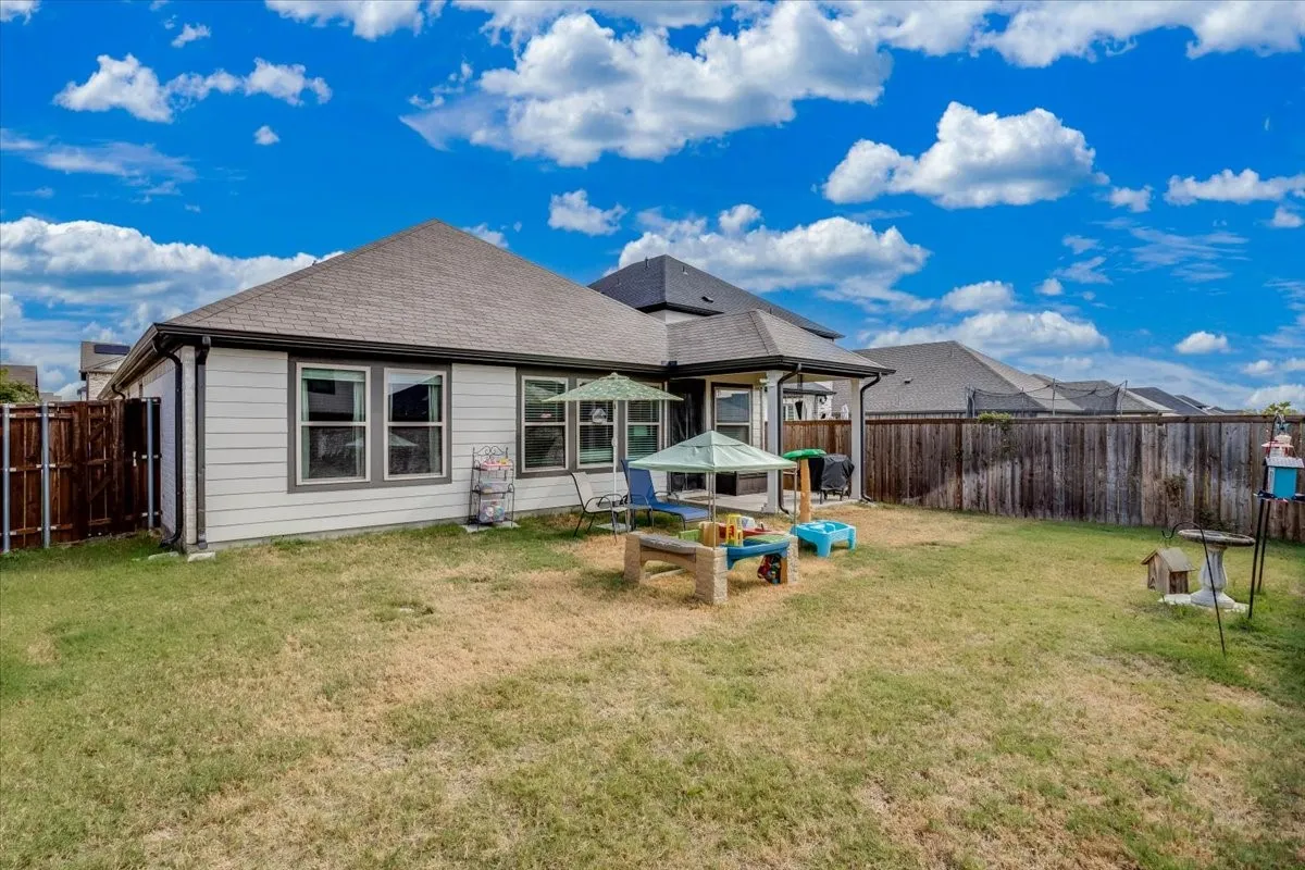 Expansive backyard featuring a privacy fence, multiple windows, and a covered patio area