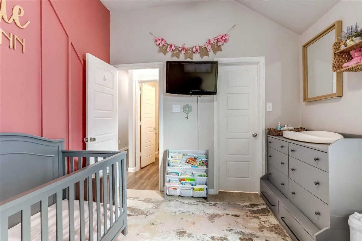 Vaulted ceiling, paneled accent wall, wood-finish interior doors, built-in dresser with storage, and wall-mounted mirror