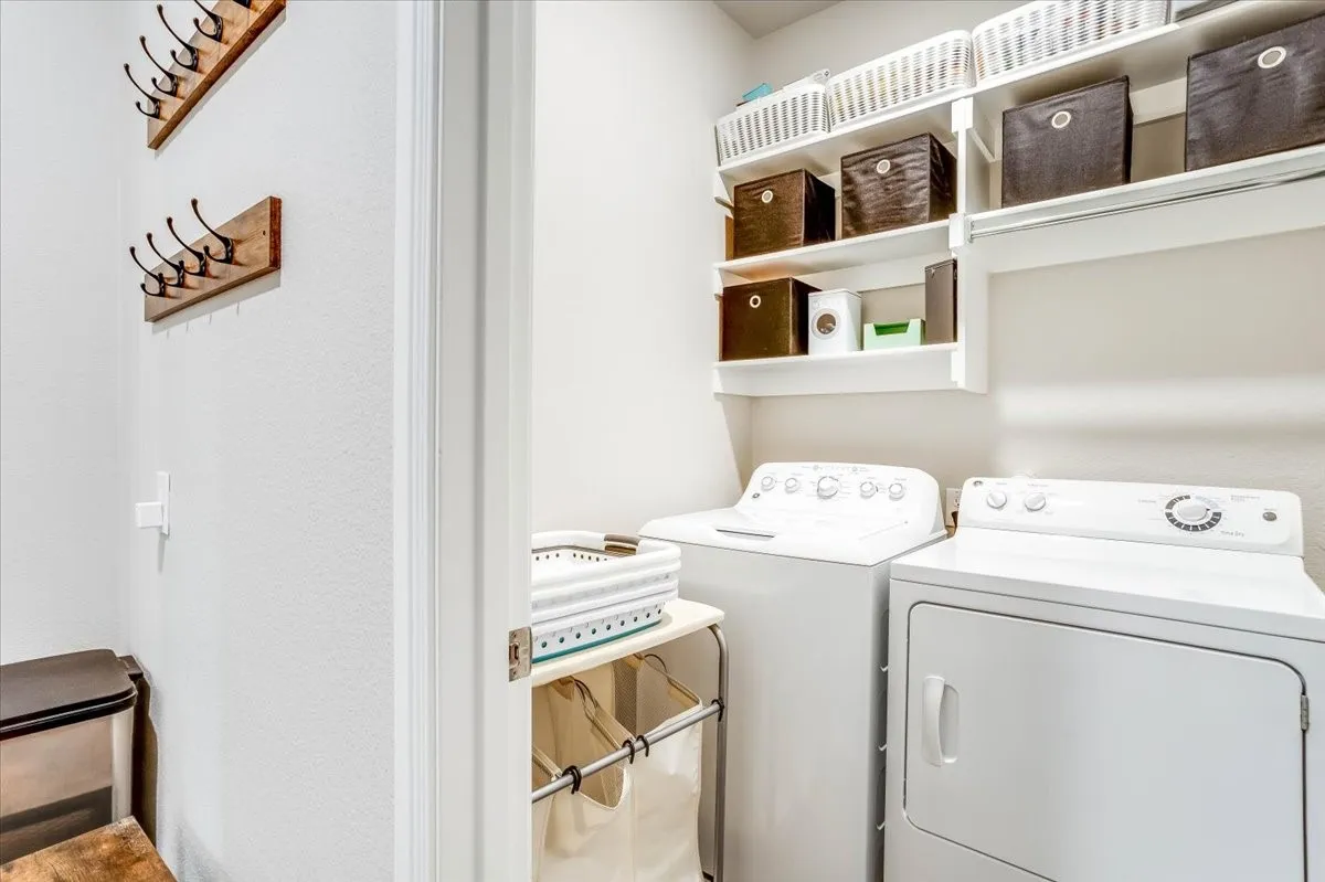 Laundry area featuring a top-load washer, front-load dryer, and wall-mounted shelving for storage