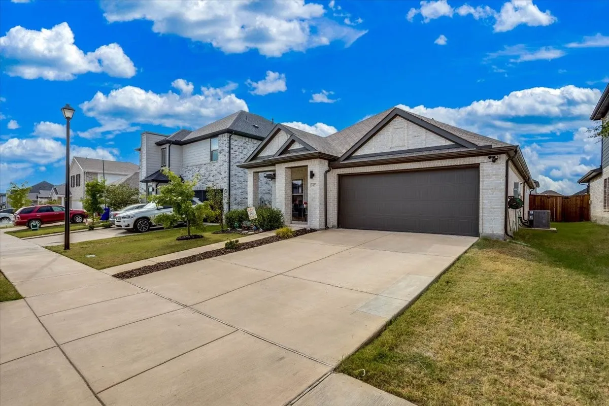 Brick and siding exterior with a dark-toned garage door, concrete driveway, and front lawn