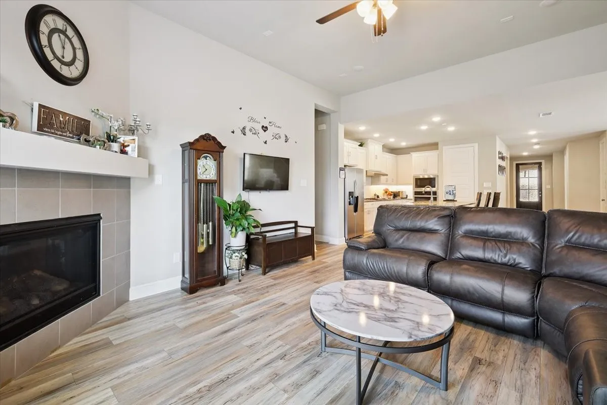 Living area featuring recessed lighting, light wood finished floors, a tile fireplace, and a ceiling fan