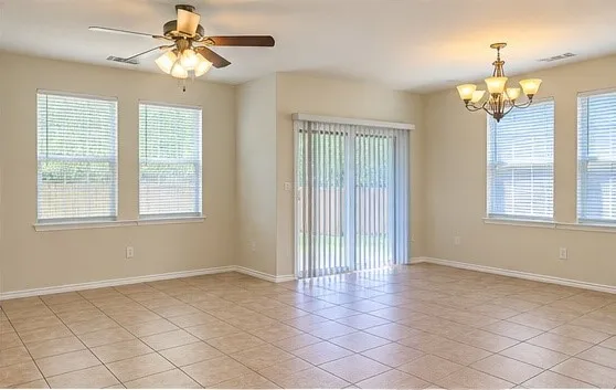 Neutral-toned tiled flooring, multiple windows with blinds, a ceiling fan, and a chandelier lighting fixture