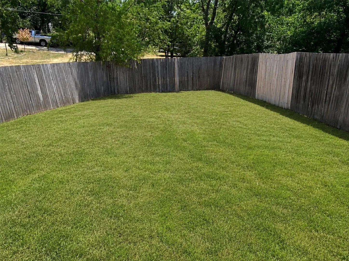 Expansive lawn area enclosed by a wood plank fence