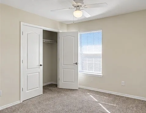 Carpeted flooring, white trim, recessed closet, ceiling fan with integrated lighting, and a single window with blinds