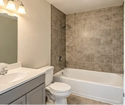Full bathroom featuring a single vanity with storage, a tiled tub/shower combination, and chrome fixtures