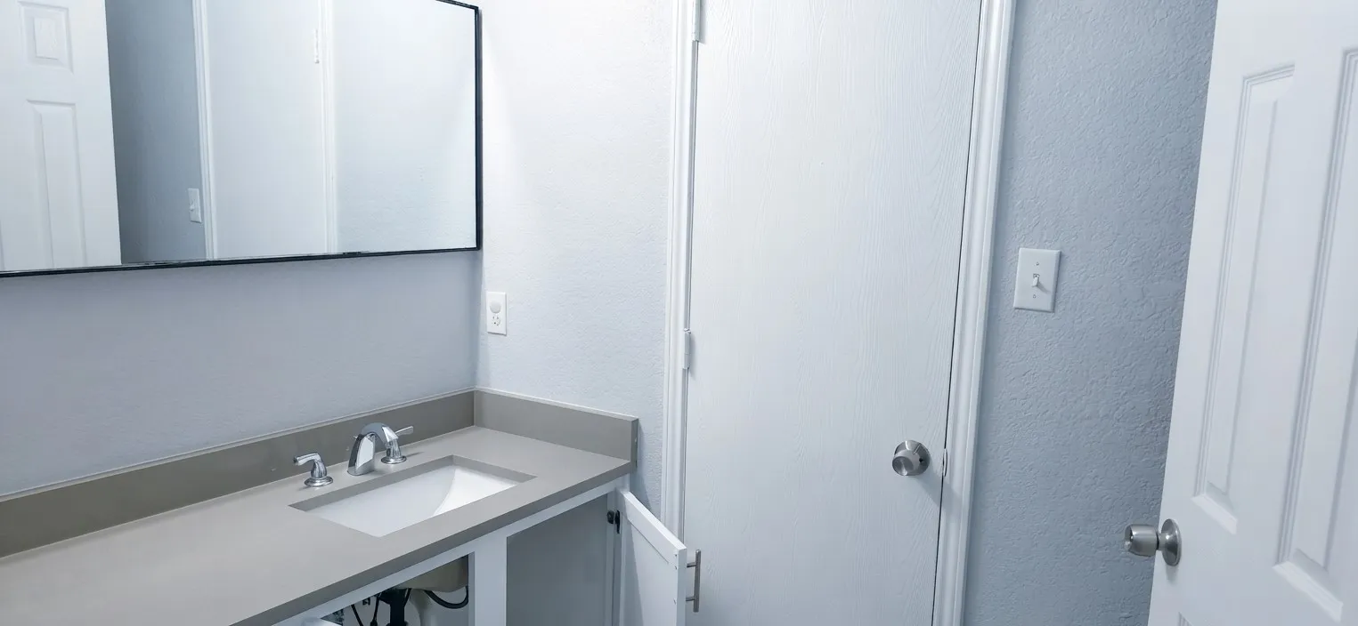 Integrated vanity with an undermount sink, chrome faucet, and a rectangular framed mirror