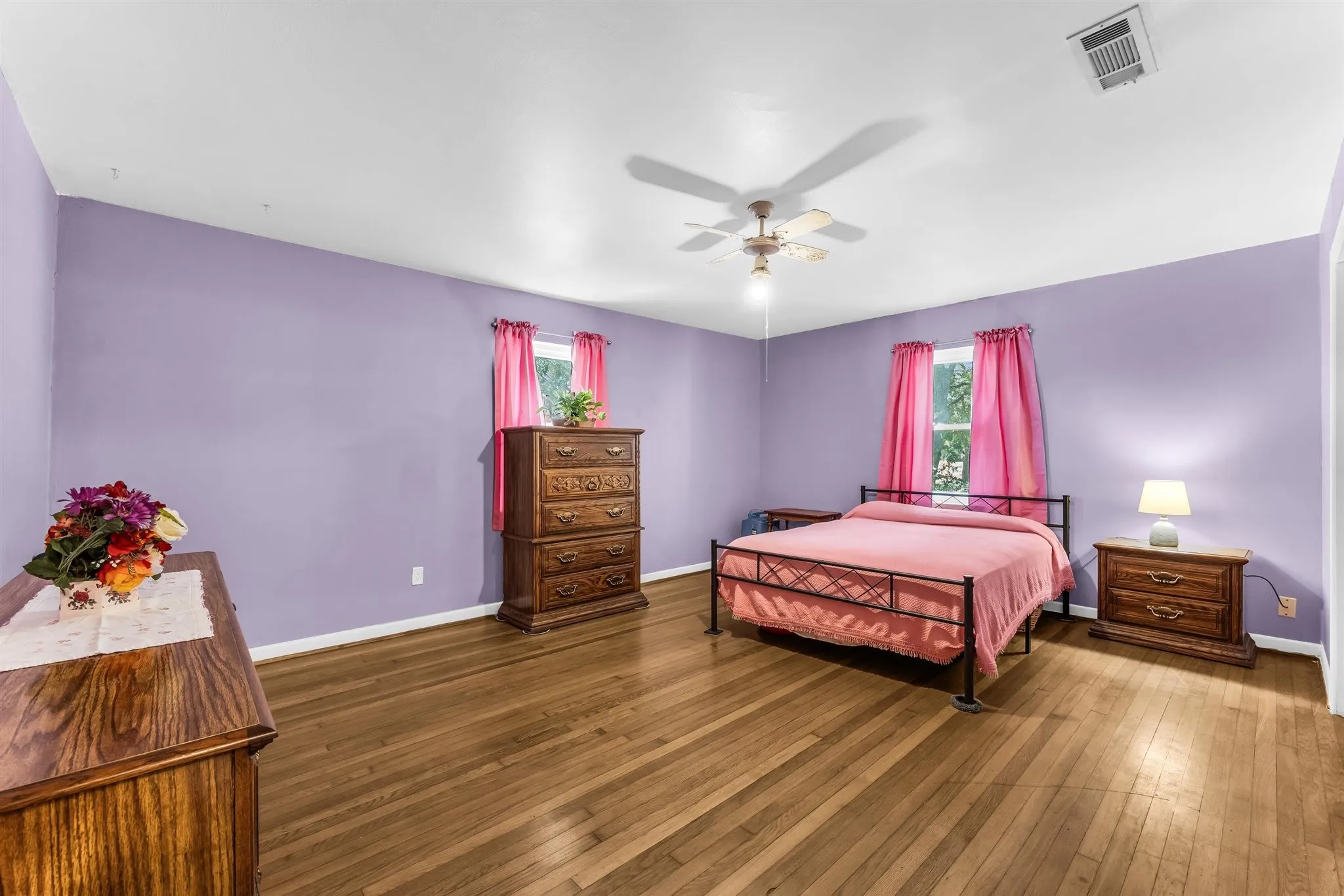 Hardwood flooring throughout, ceiling fan with light fixture, and multiple windows allowing natural light