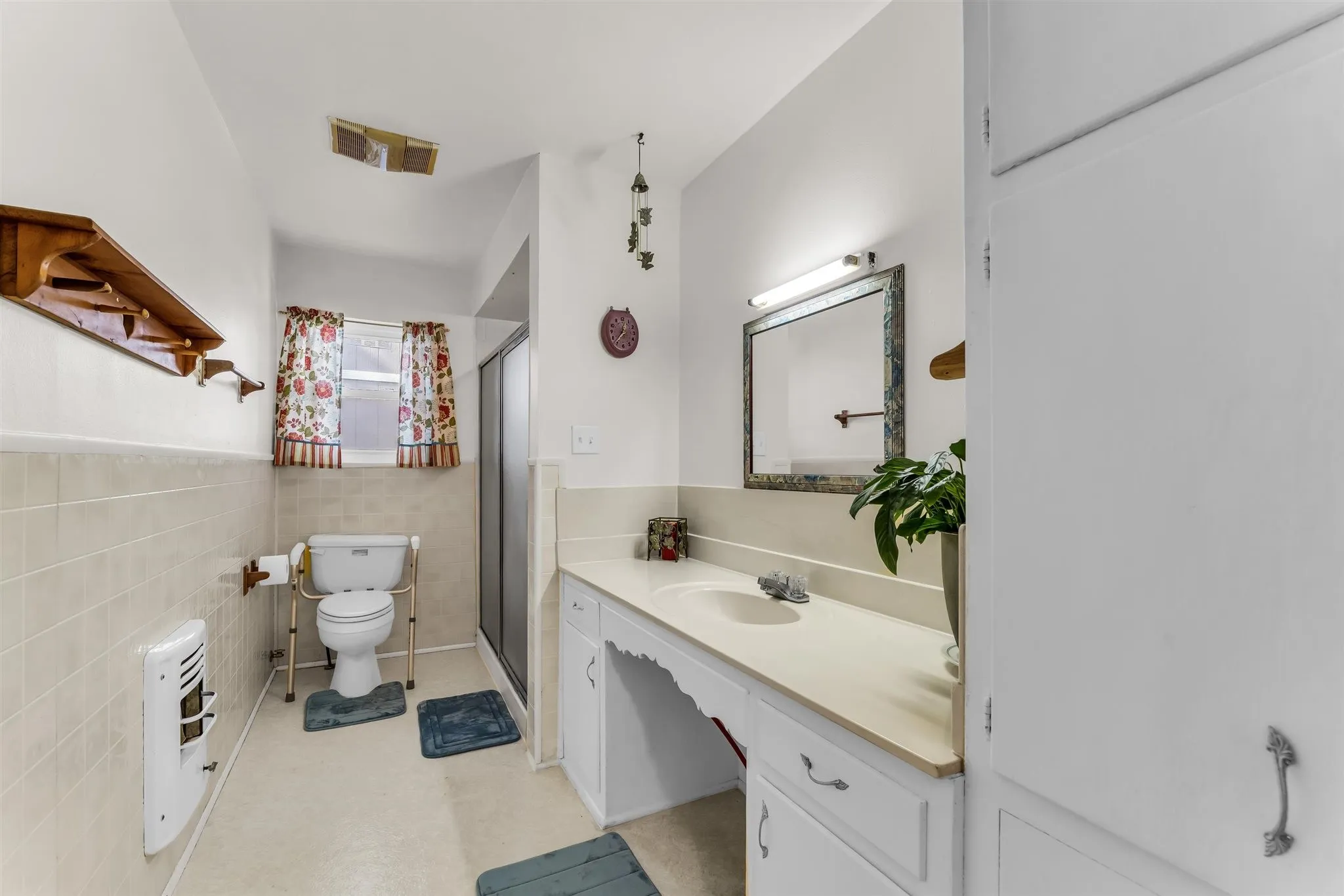 Bathroom featuring a vanity with integrated sink, built-in storage cabinetry, tiled walls, and a shower enclosure