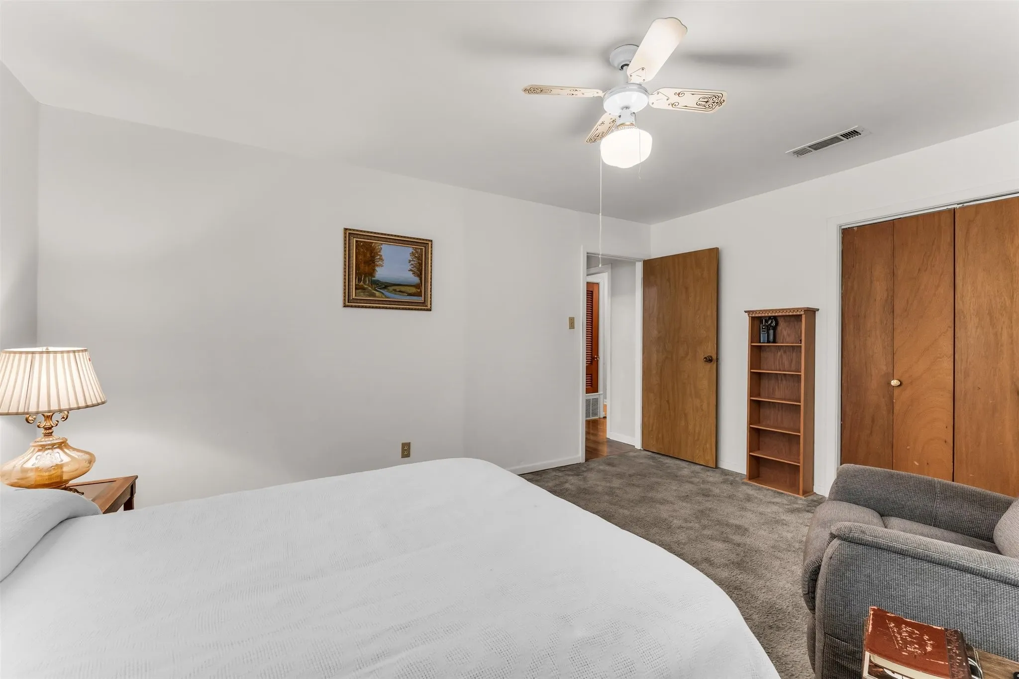 Textured carpeting, wood-finish doors, white walls, and a ceiling fan with integrated lighting